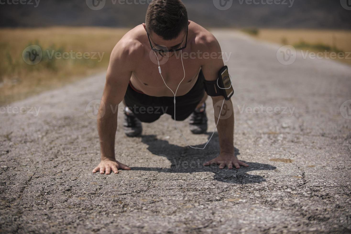 Male athlete exercising push up outside in sunny sunshine. Fit shirtless male fitness model in crossfit exercise outdoors. Healthy lifestyle concept. photo