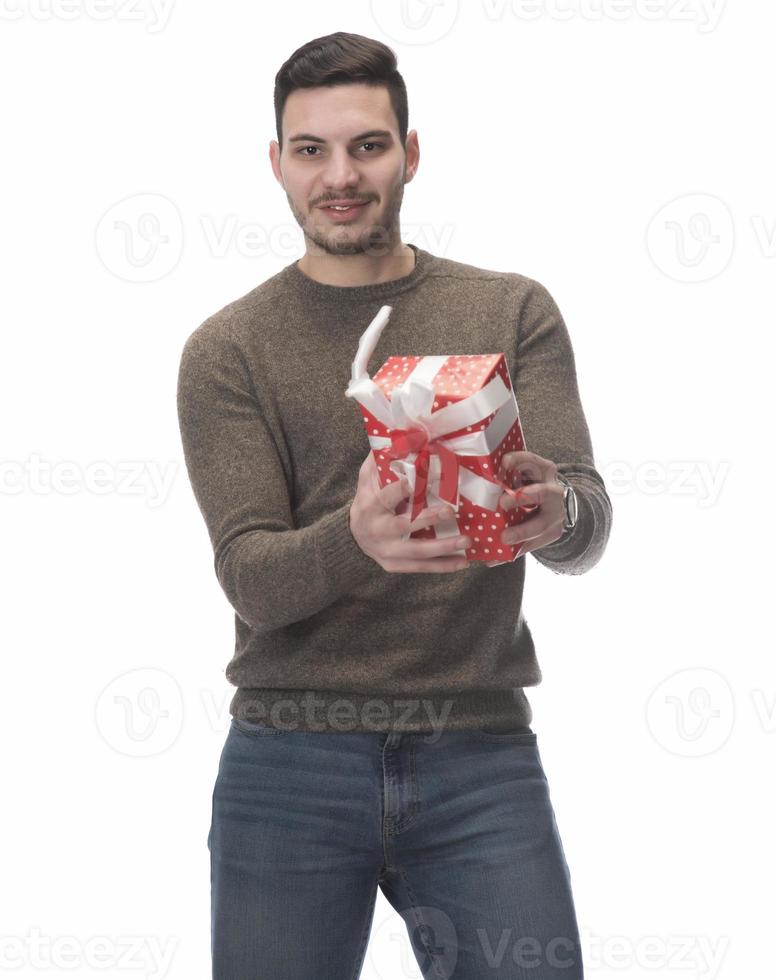 Young handsome man holding birthday present, looking positive and happy standing and smiling with a confident smile photo