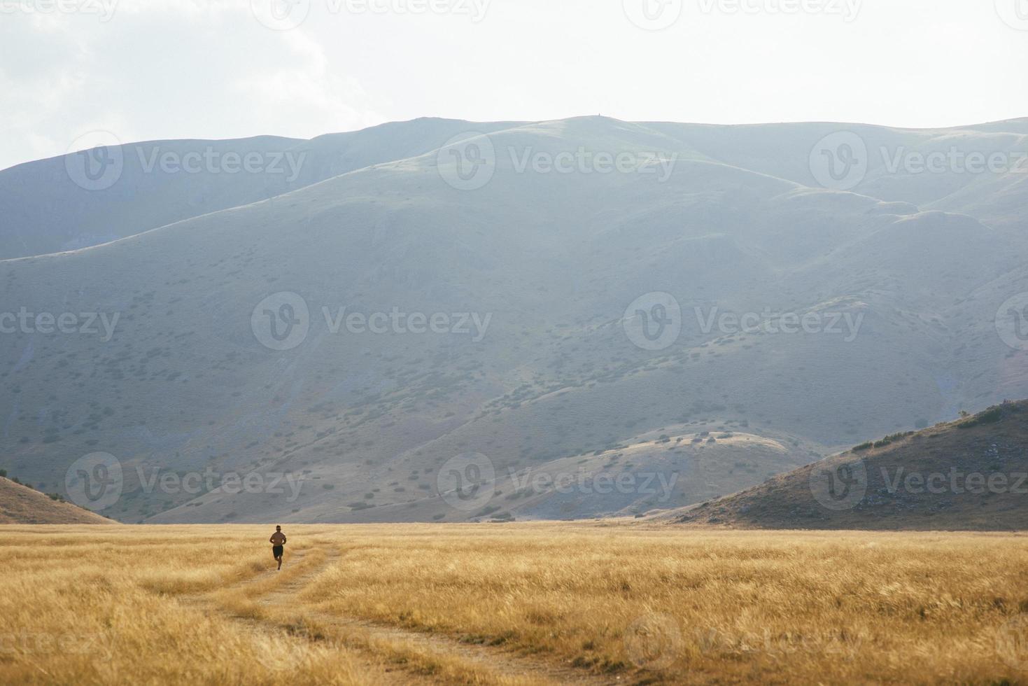 sporty man runner running on mountain plateau in summer photo