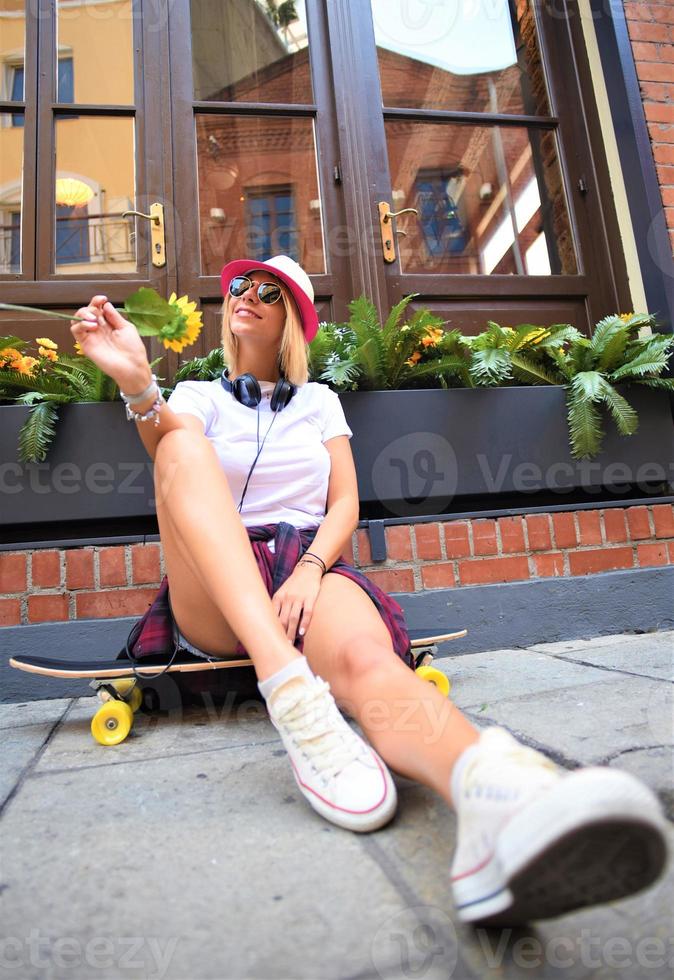 Beautiful hipster girl with skate board wearing sunglasses in the city. photo