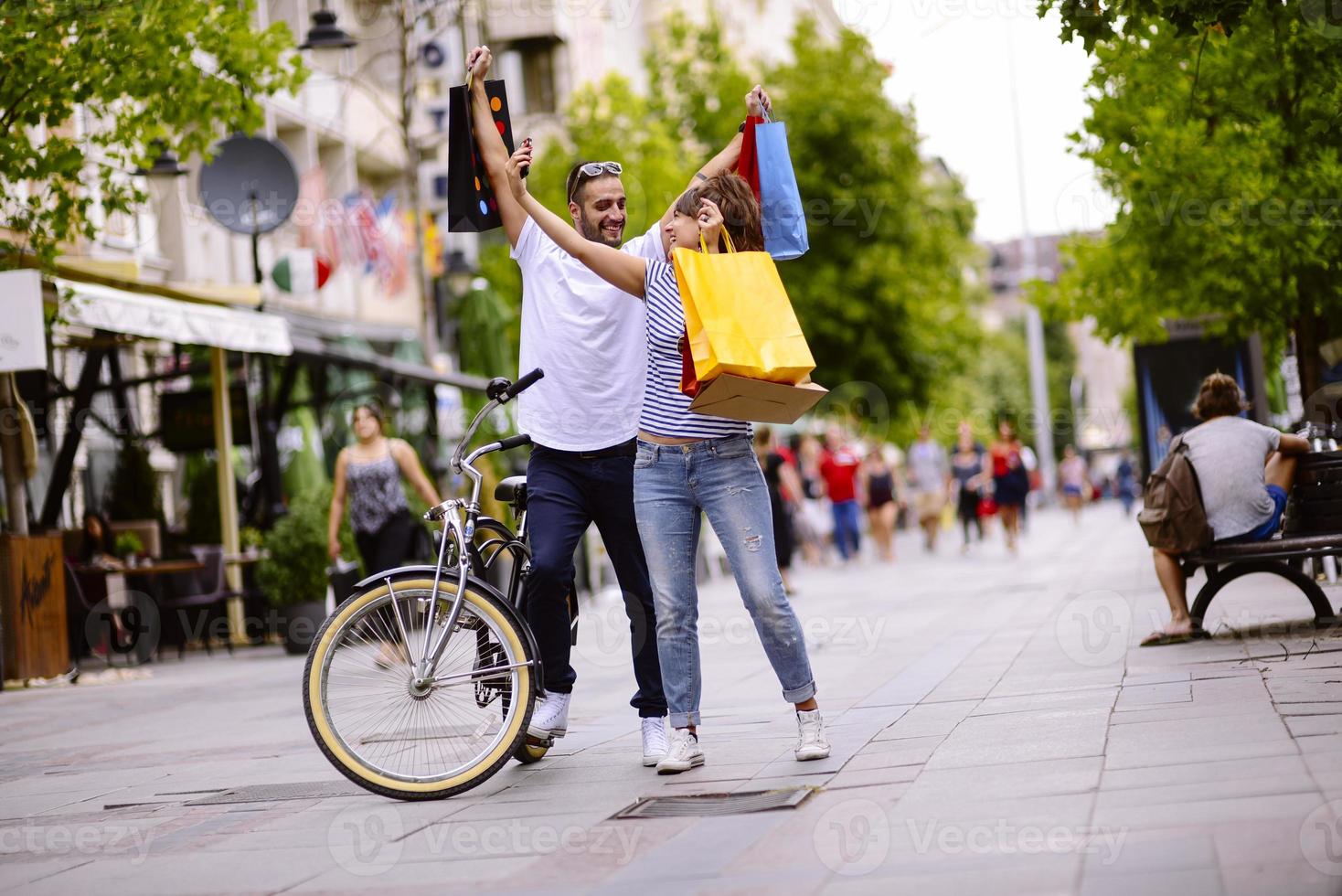 Portrait of cheerful Caucasian young couple man and woman holding many paper bags after shopping while walking and talking on street. Happy family couple with packages outdoor. Buying concept photo