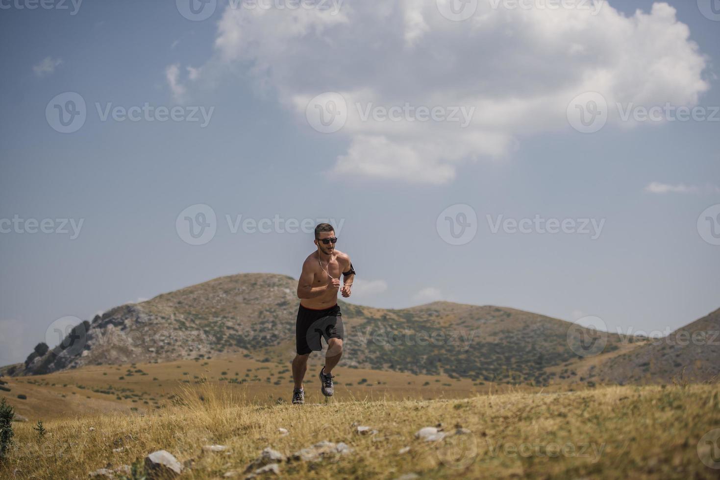 corredor de hombre deportivo corriendo en la meseta de la montaña en verano foto