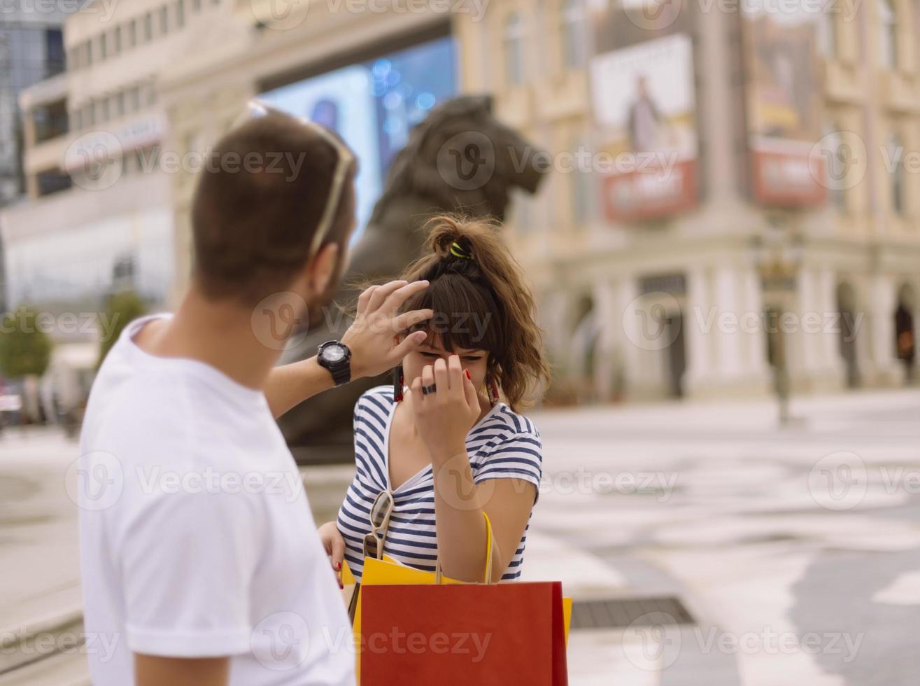 Portrait of cheerful Caucasian young couple man and woman holding many paper bags after shopping while walking and talking on street. Happy family couple with packages outdoor. Buying concept photo