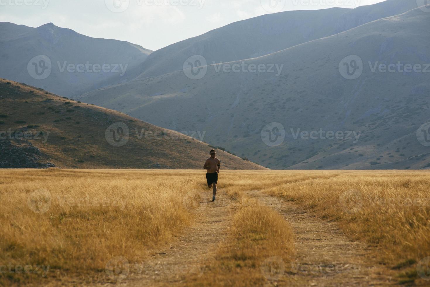 sporty man runner running on mountain plateau in summer photo