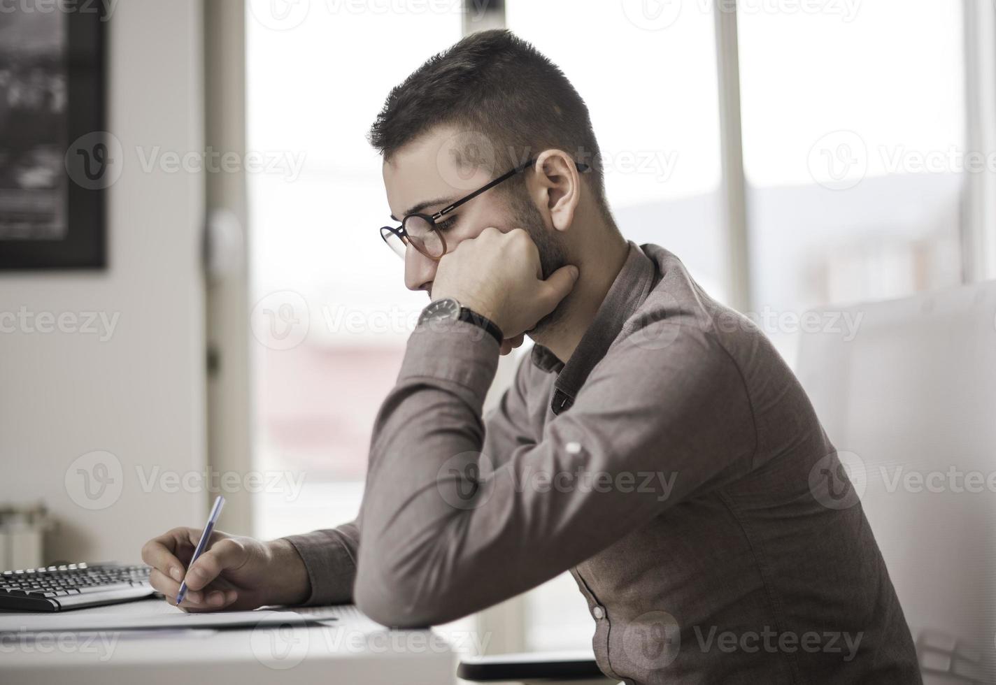 man using computer while sitting on chair. Businessman using mouse with mobile phone on table. photo