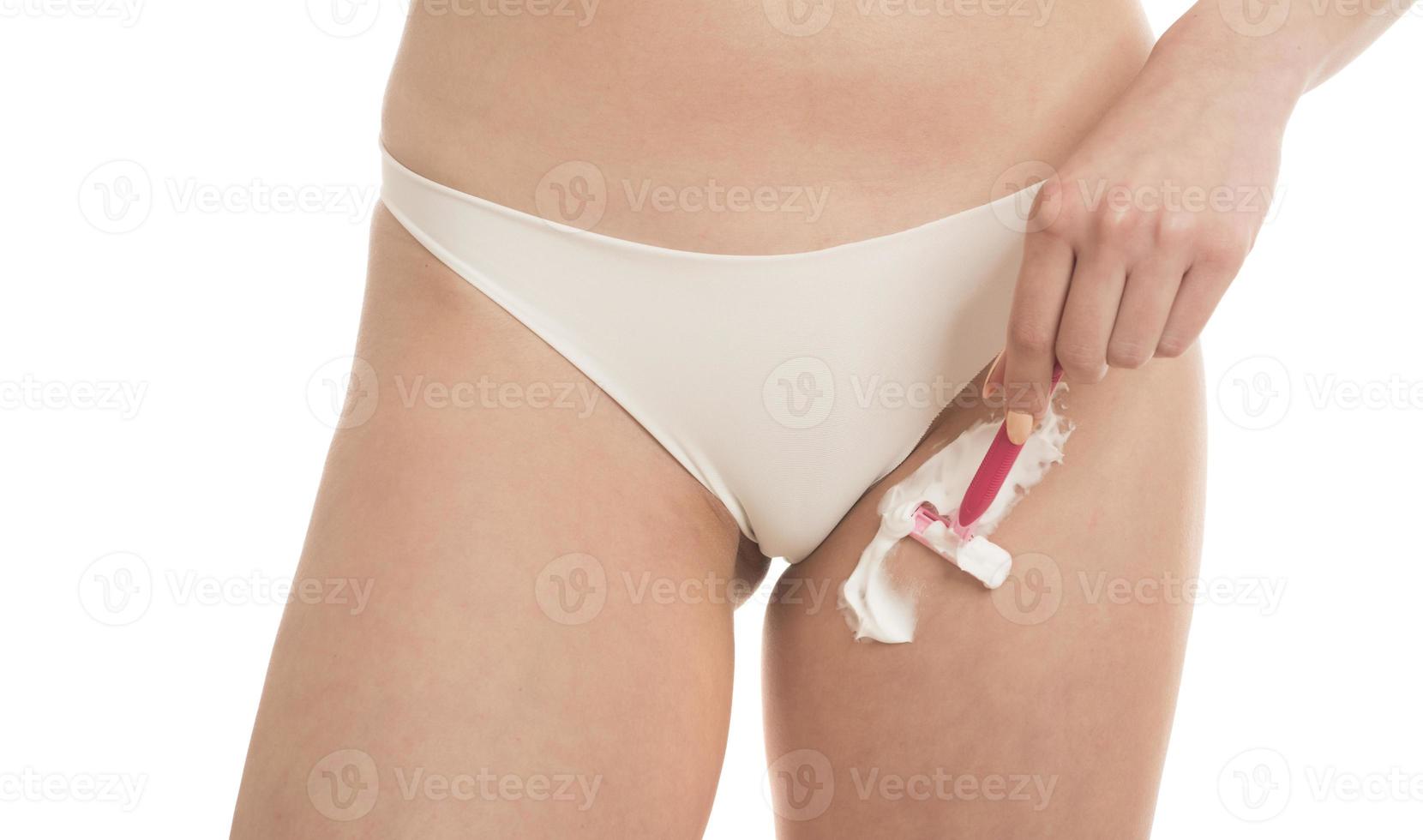 A girl in white panties shaves her hair in the bikini area with a razor photo