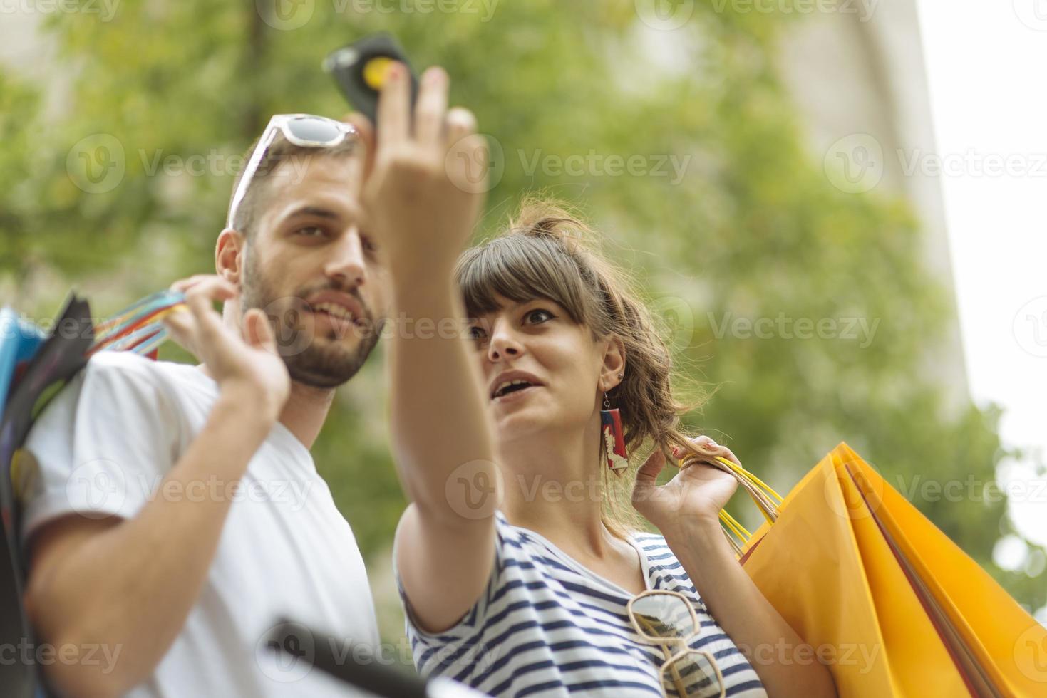 Portrait of cheerful Caucasian young couple man and woman holding many paper bags after shopping while walking and talking on street. Happy family couple with packages outdoor. Buying concept photo