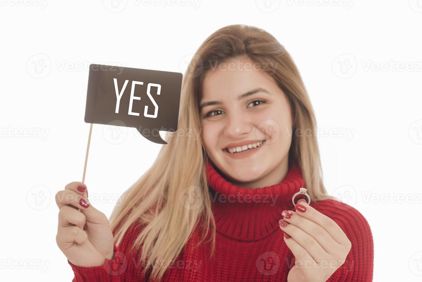 Woman holding engagement ring and sign saying YES photo
