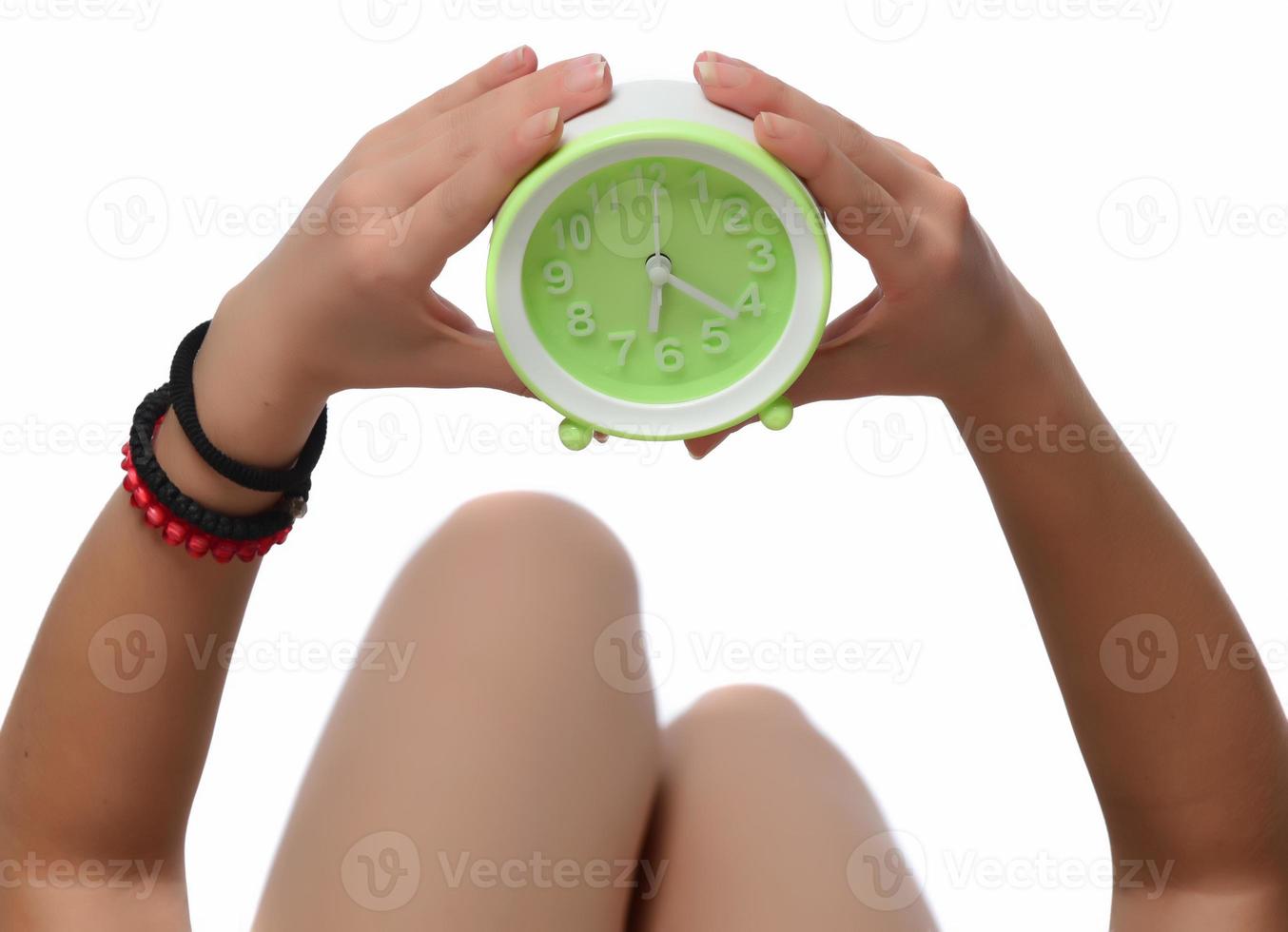 Happy young woman holding clock over isolated white background photo