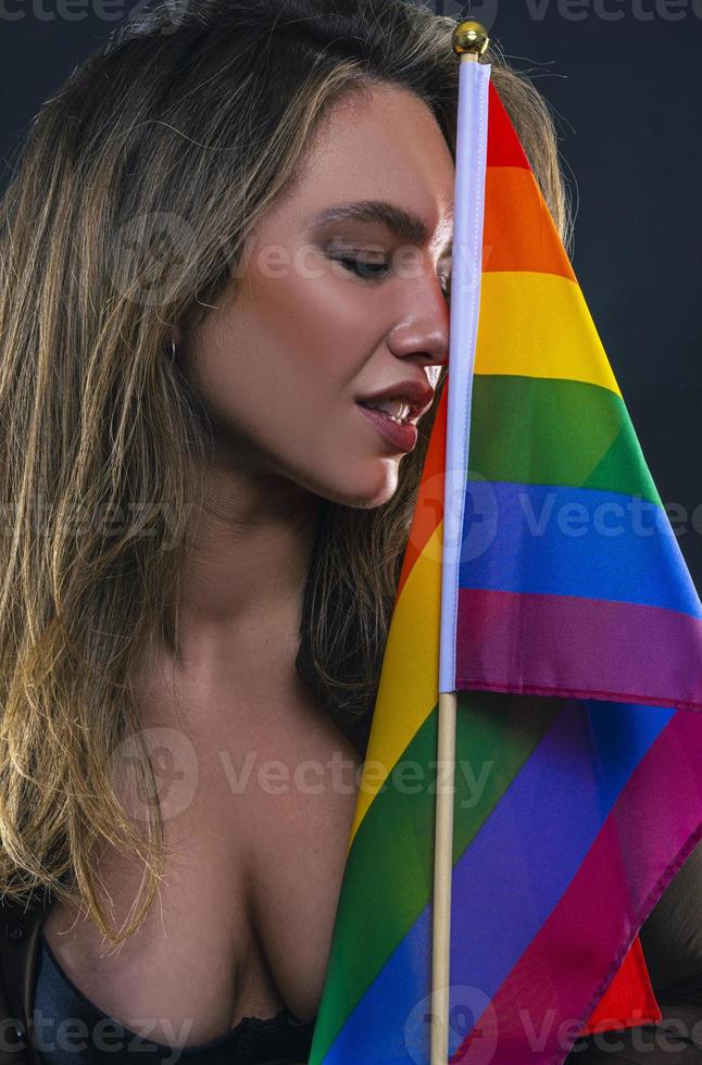 Lesbian woman holding rainbow flag isolated on black background. LGBT International symbol of the lesbian, gay, bisexual and transgender community. photo