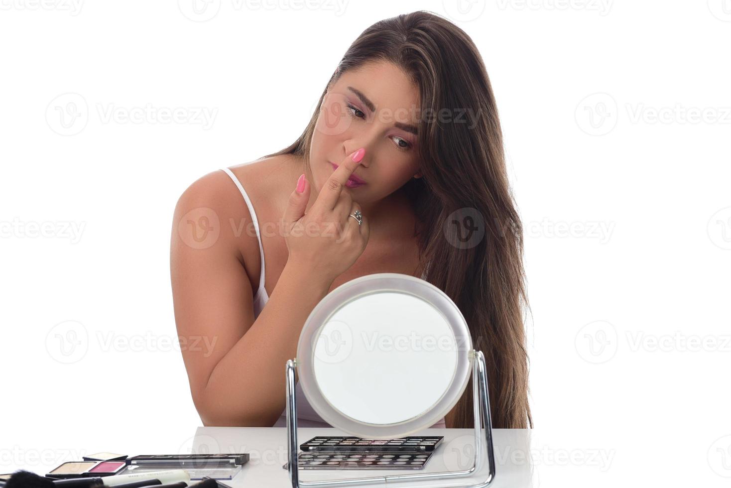 young woman checks her face skin in the mirror photo