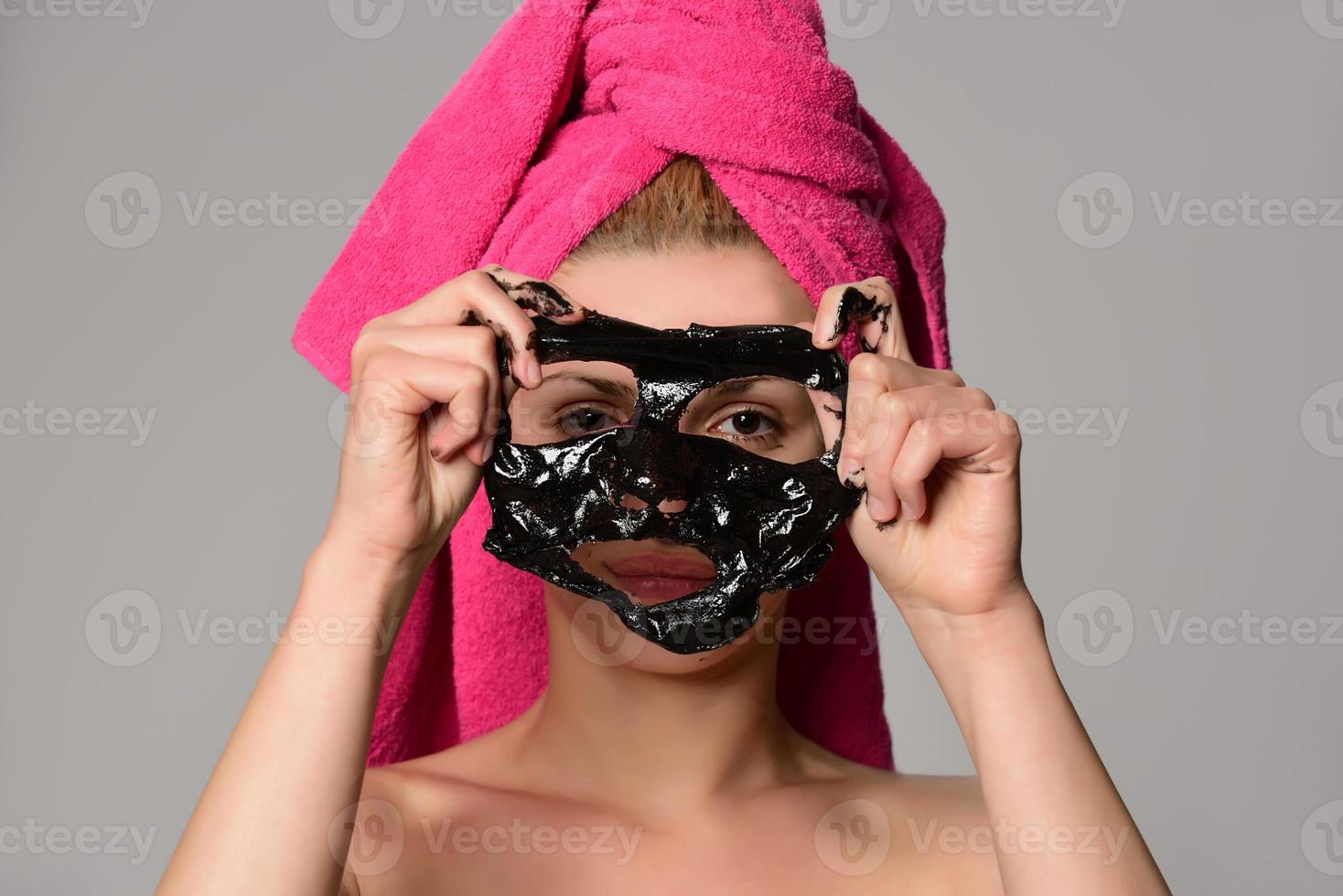 beautiful female model with black facial cosmetic mask. Isolated on gray background photo