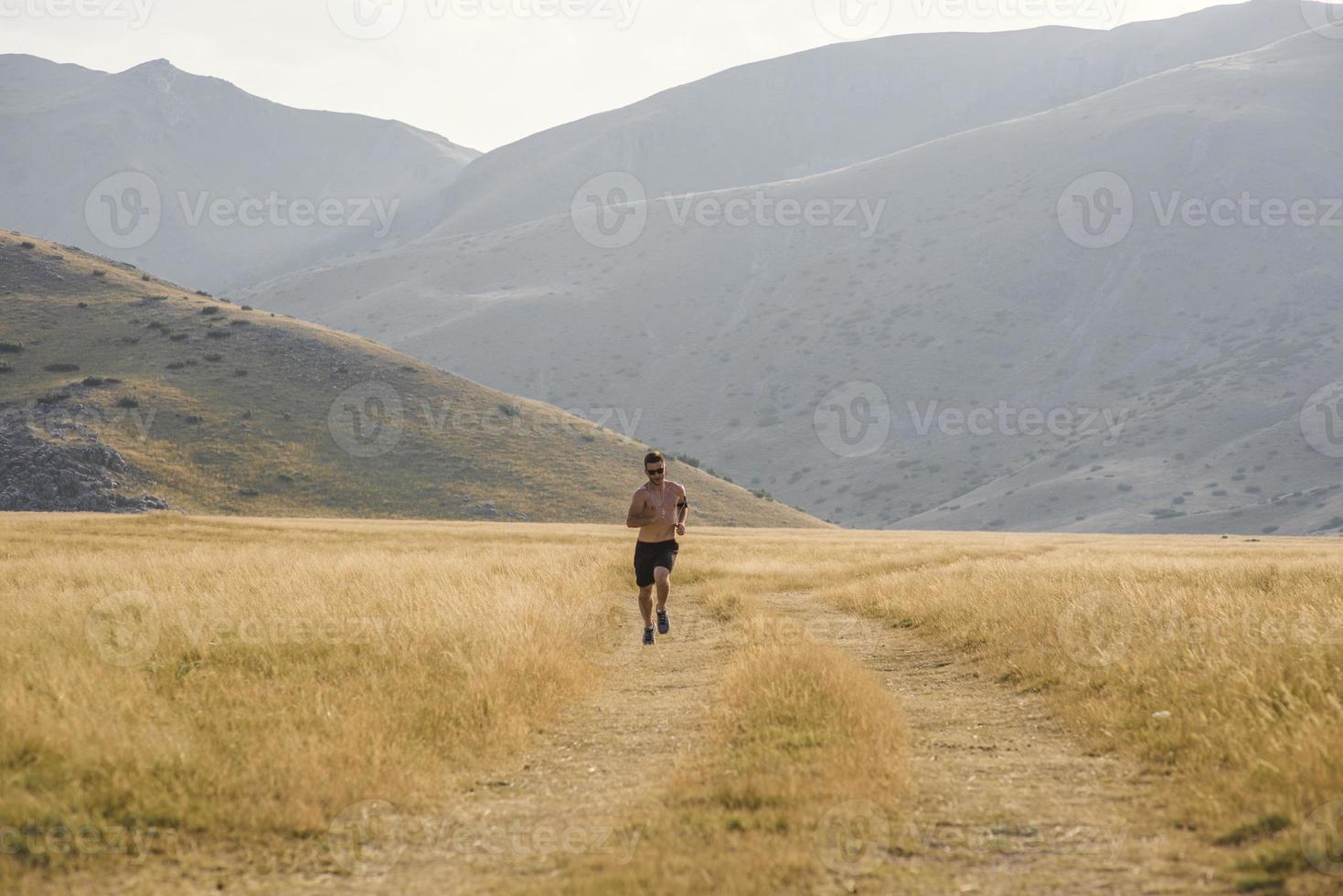 corredor de hombre deportivo corriendo en la meseta de la montaña en verano foto