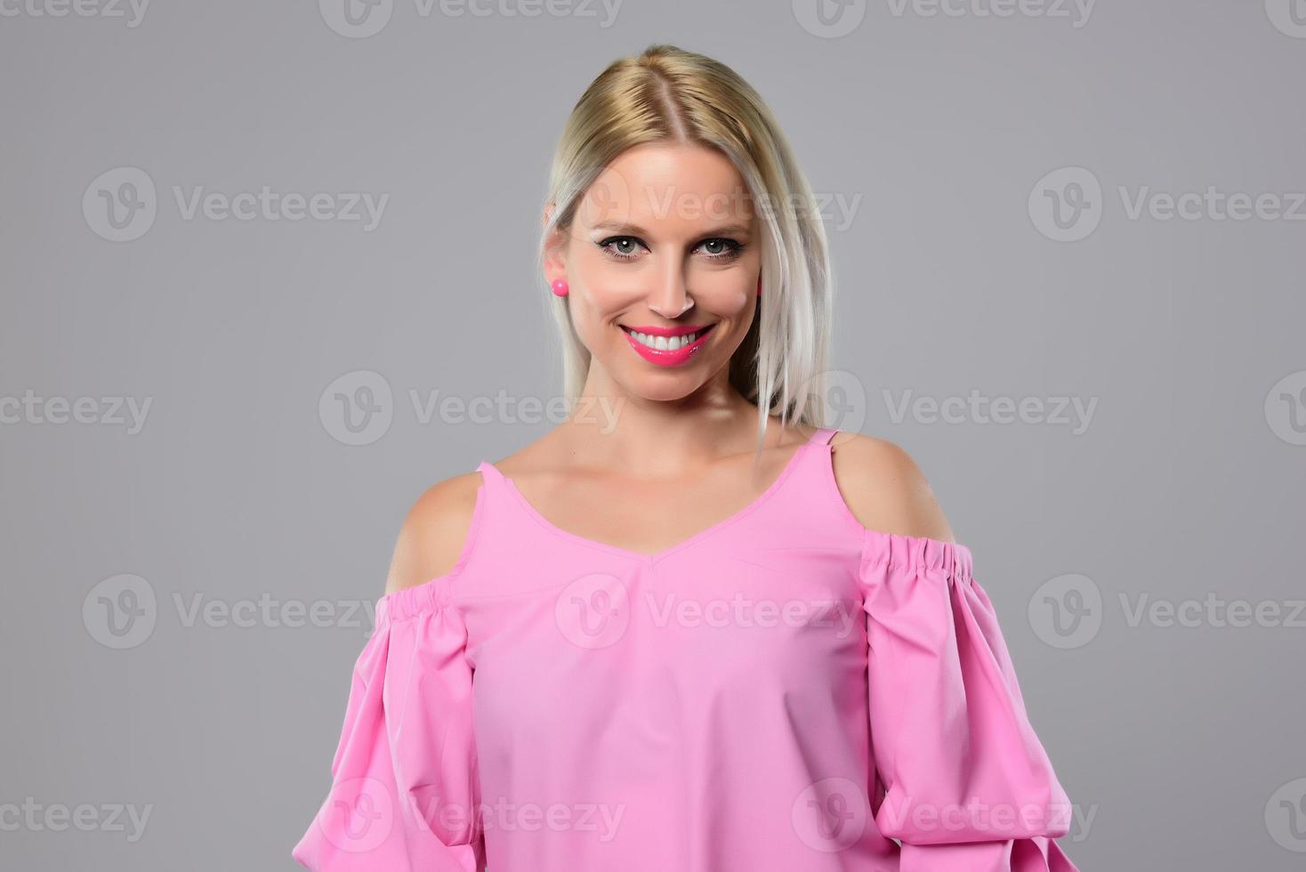 Portrait of beautiful young woman in cute pink shirt and blue jeans posing in studio. Concept of beauty, emotions, facial expression, lifestyle, fashion, youth culture photo