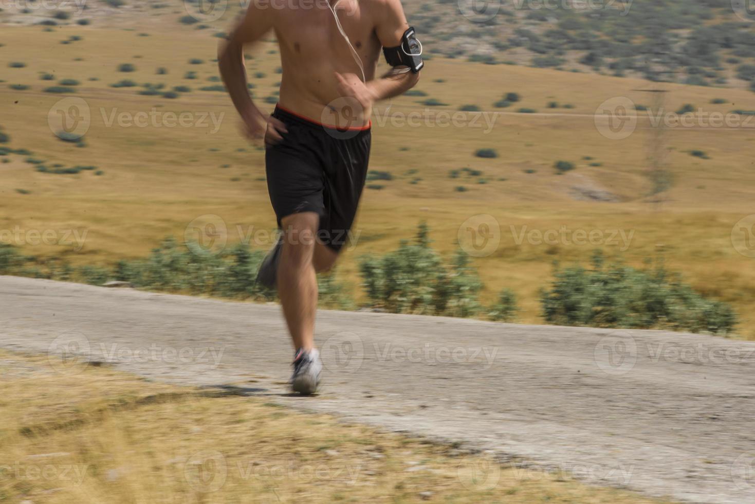 sporty man runner running on mountain plateau in summer photo