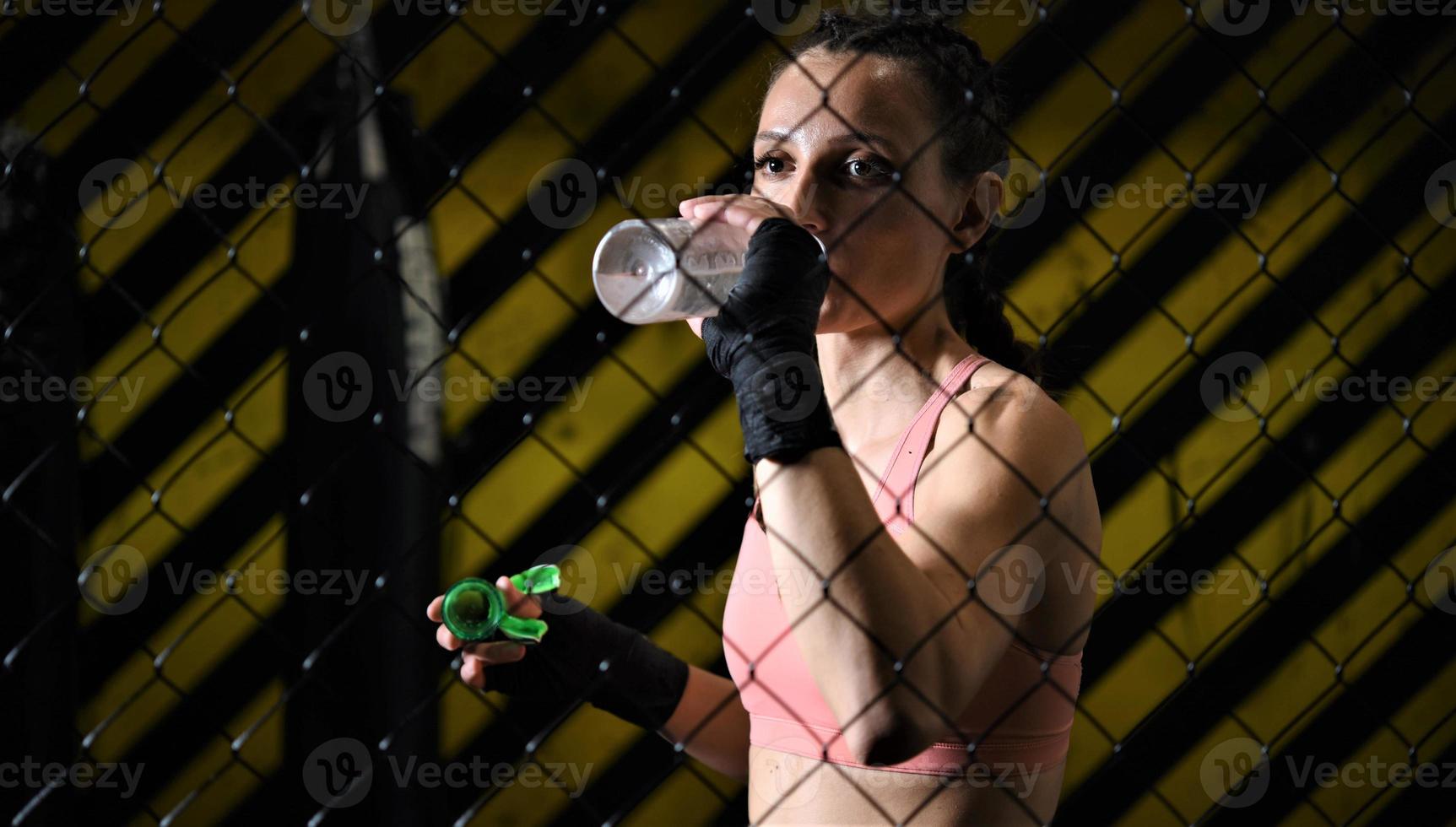 female fighter drinking water and resting after the training photo