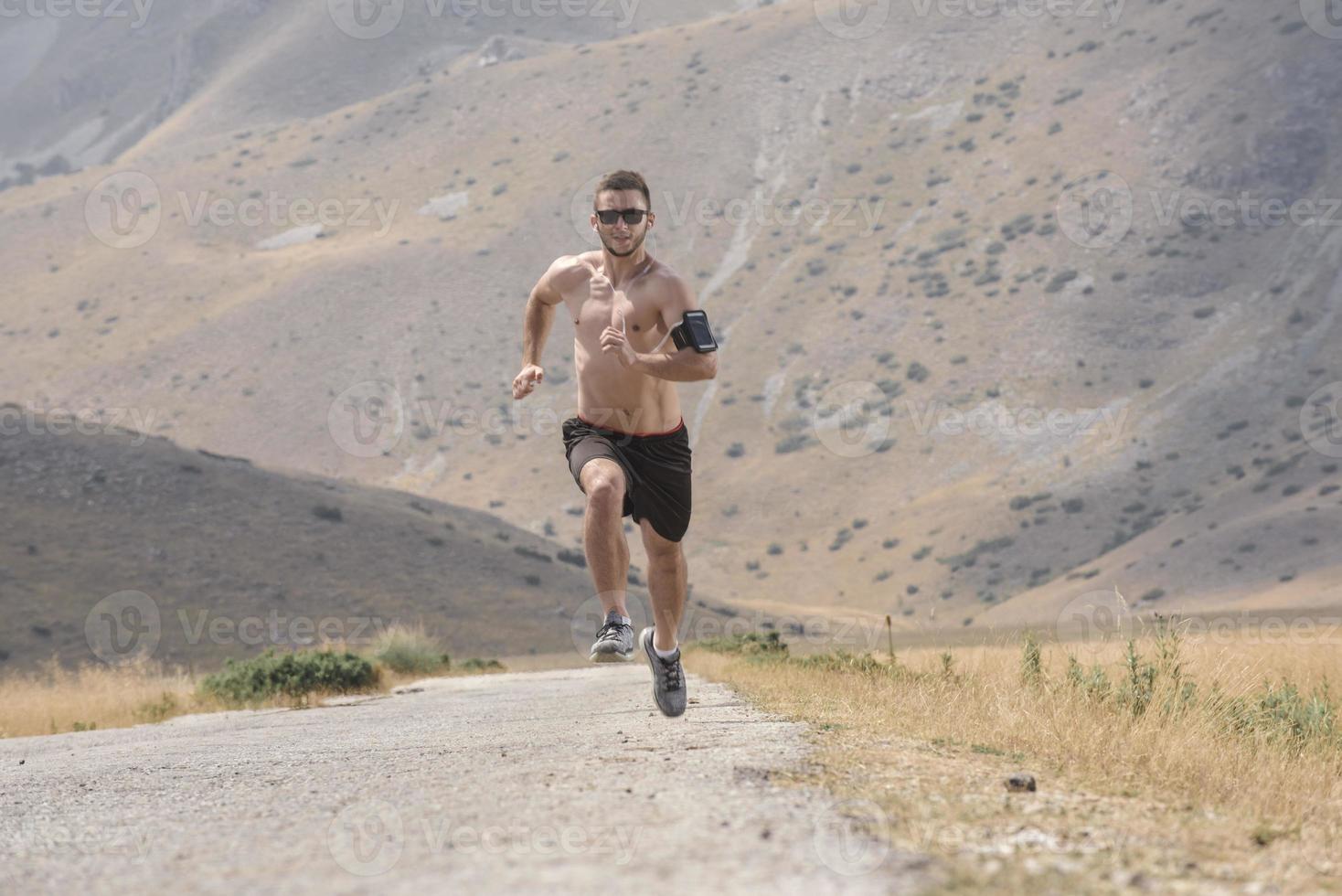 sporty man runner running on mountain plateau in summer photo