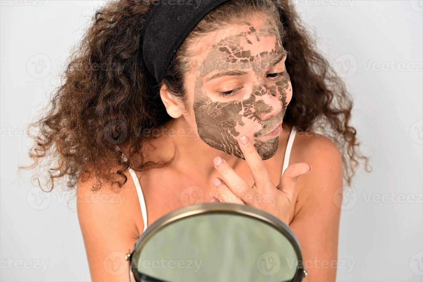 Beautiful woman having clay facial mask photo