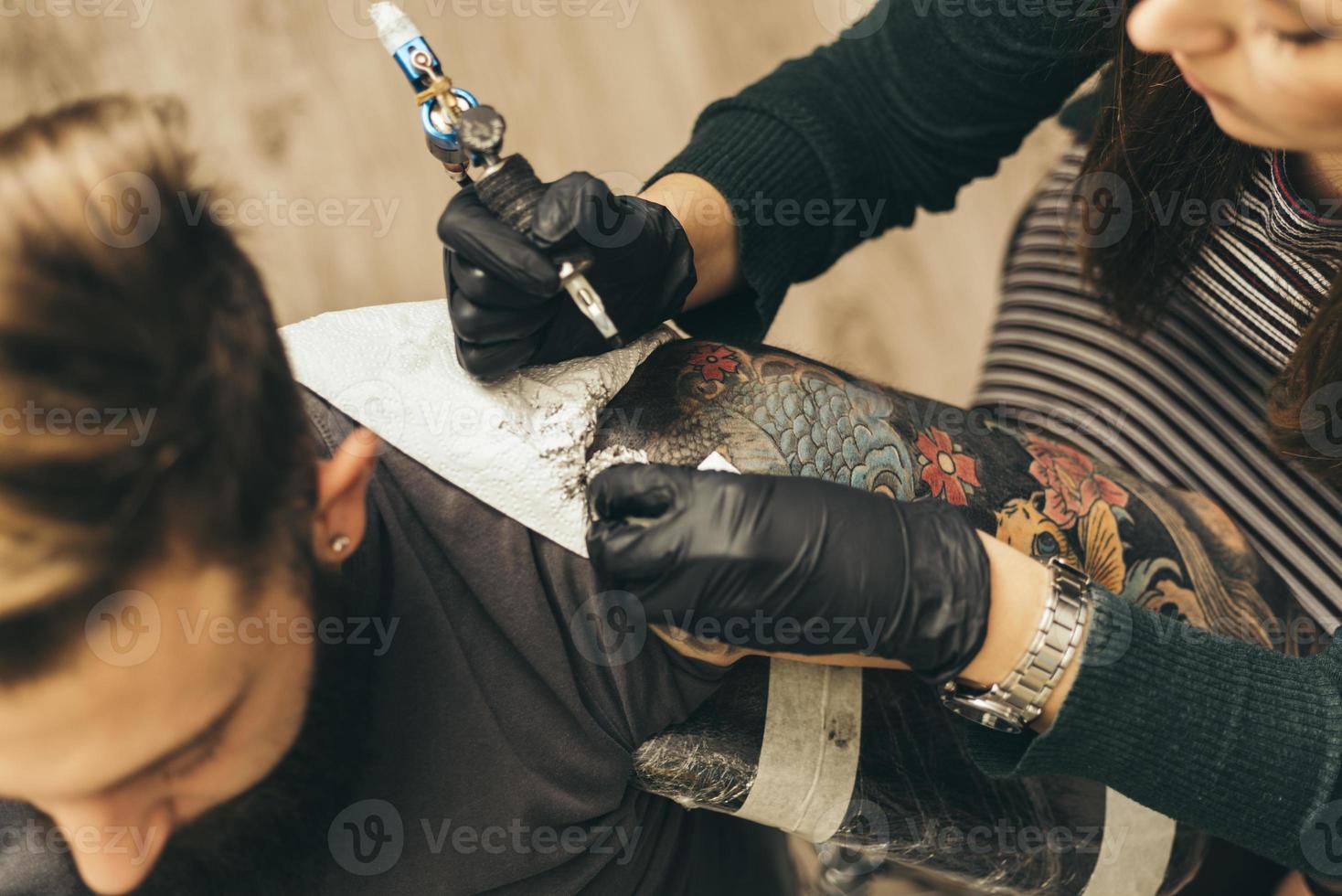 close up tattoo machine. Woman creating picture on hand with it in salon photo