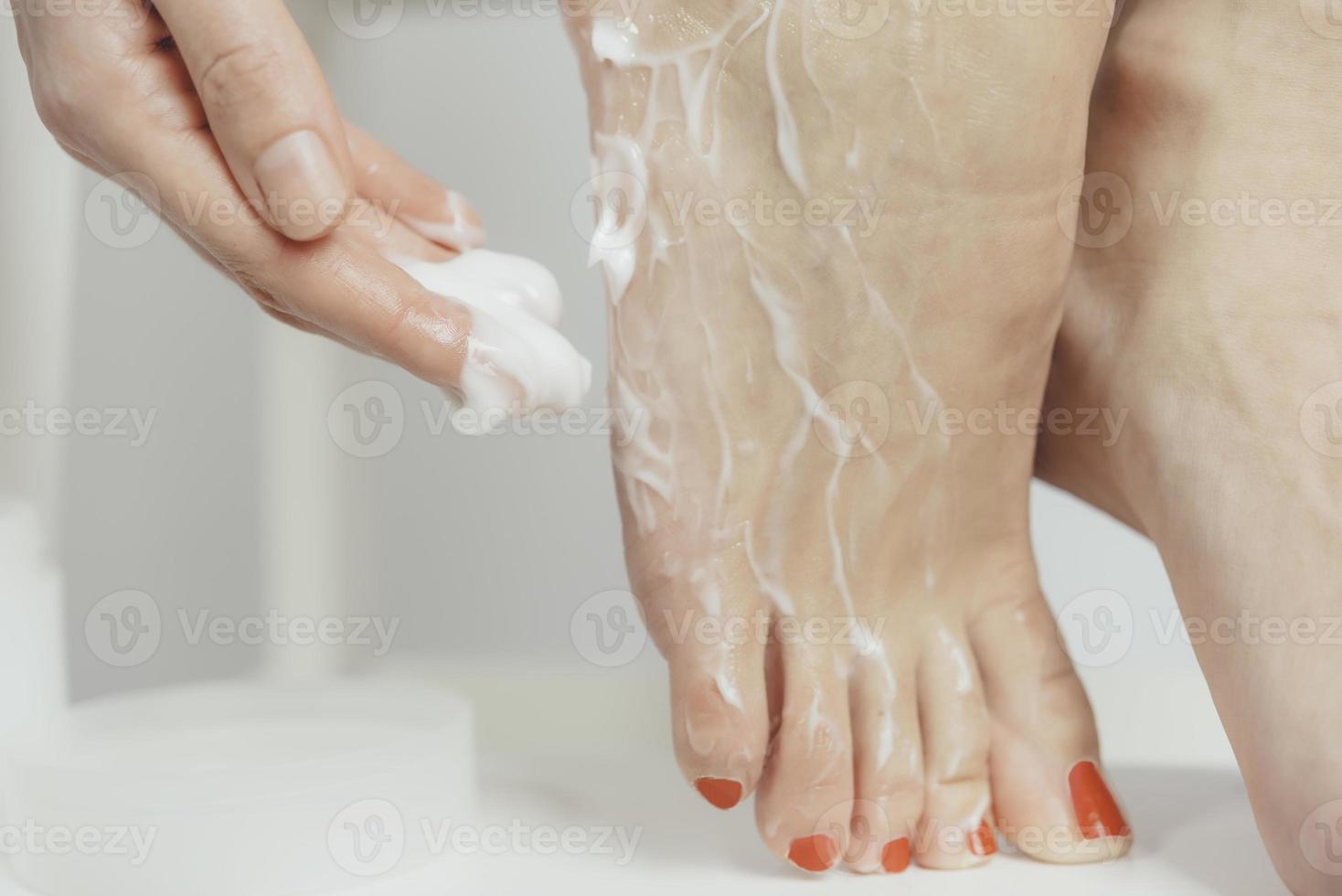 a young woman applies lotion to her feet photo