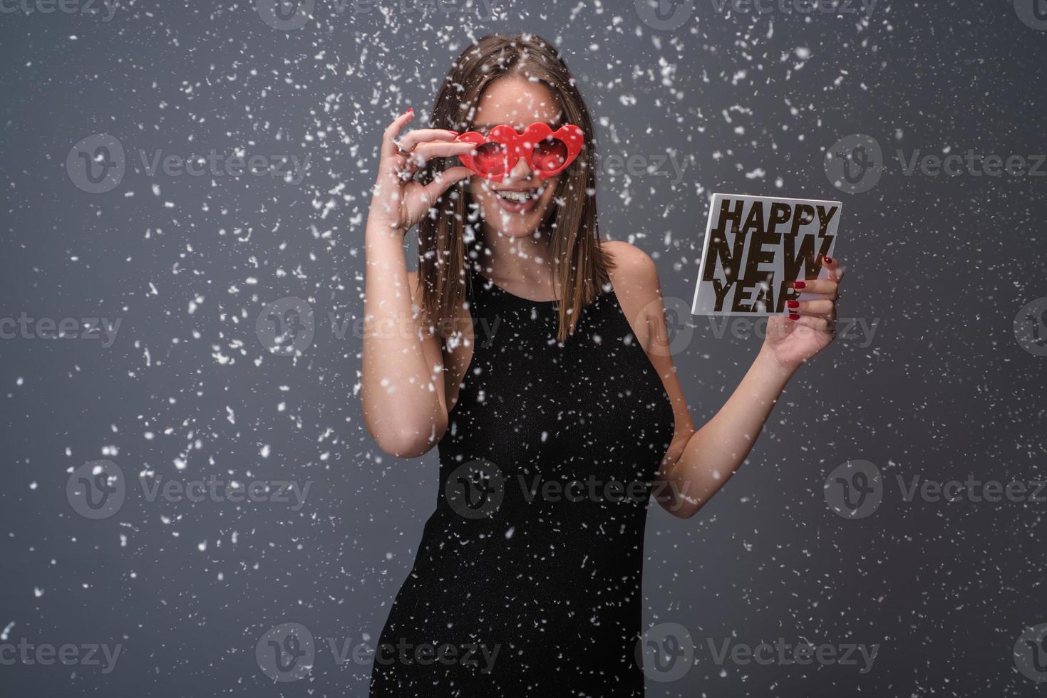 Beautiful woman celebrating New Year with confetti and champagne holding sign. isolated photo