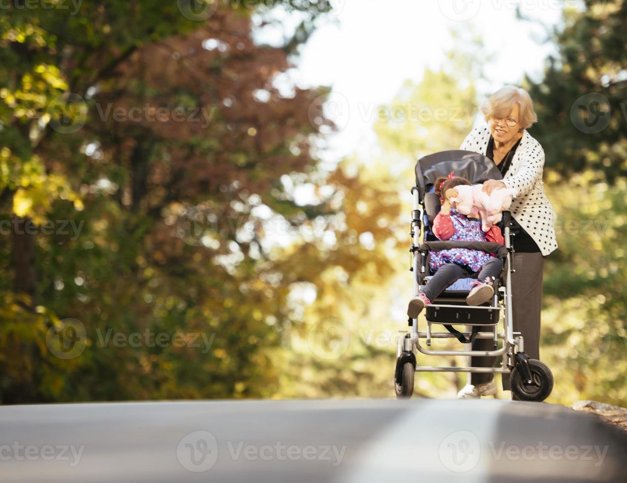 Grandmother and her autistic grand daughter enjoying holiday together outdoors, lying on green grass on blanket and smiling to camera. Leisure family lifestyle, happiness and moments. photo