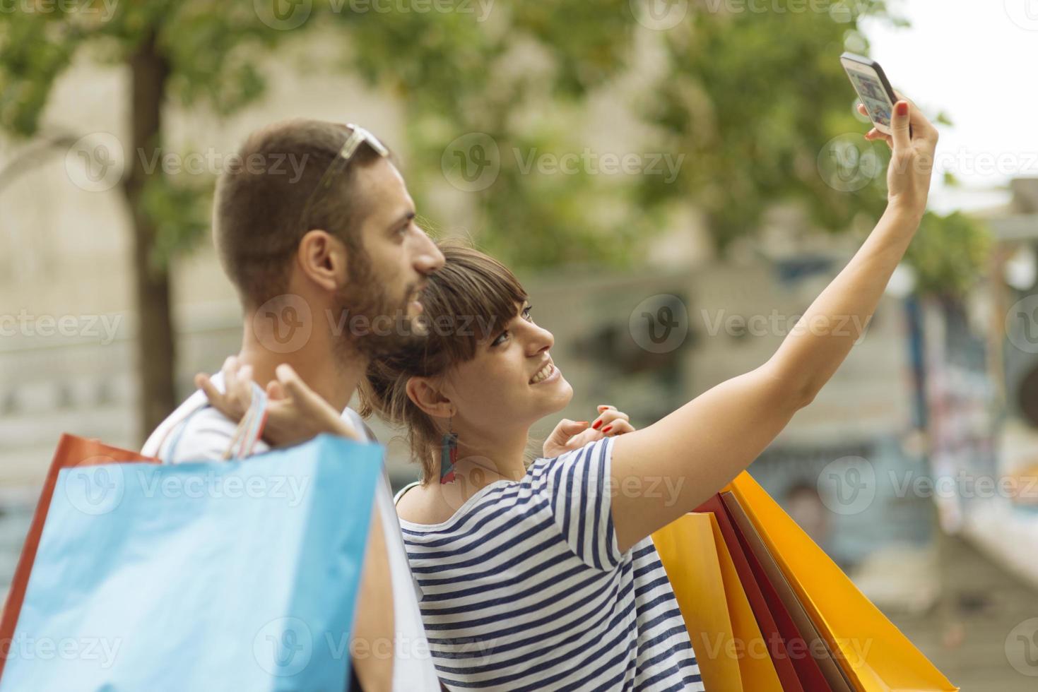 Portrait of cheerful Caucasian young couple man and woman holding many paper bags after shopping while walking and talking on street. Happy family couple with packages outdoor. Buying concept photo