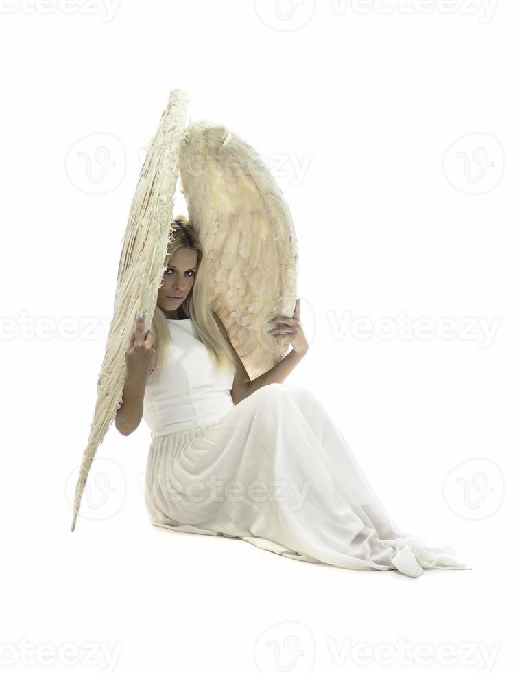 beautiful young model with big angel wings sitting in the studio. white background photo