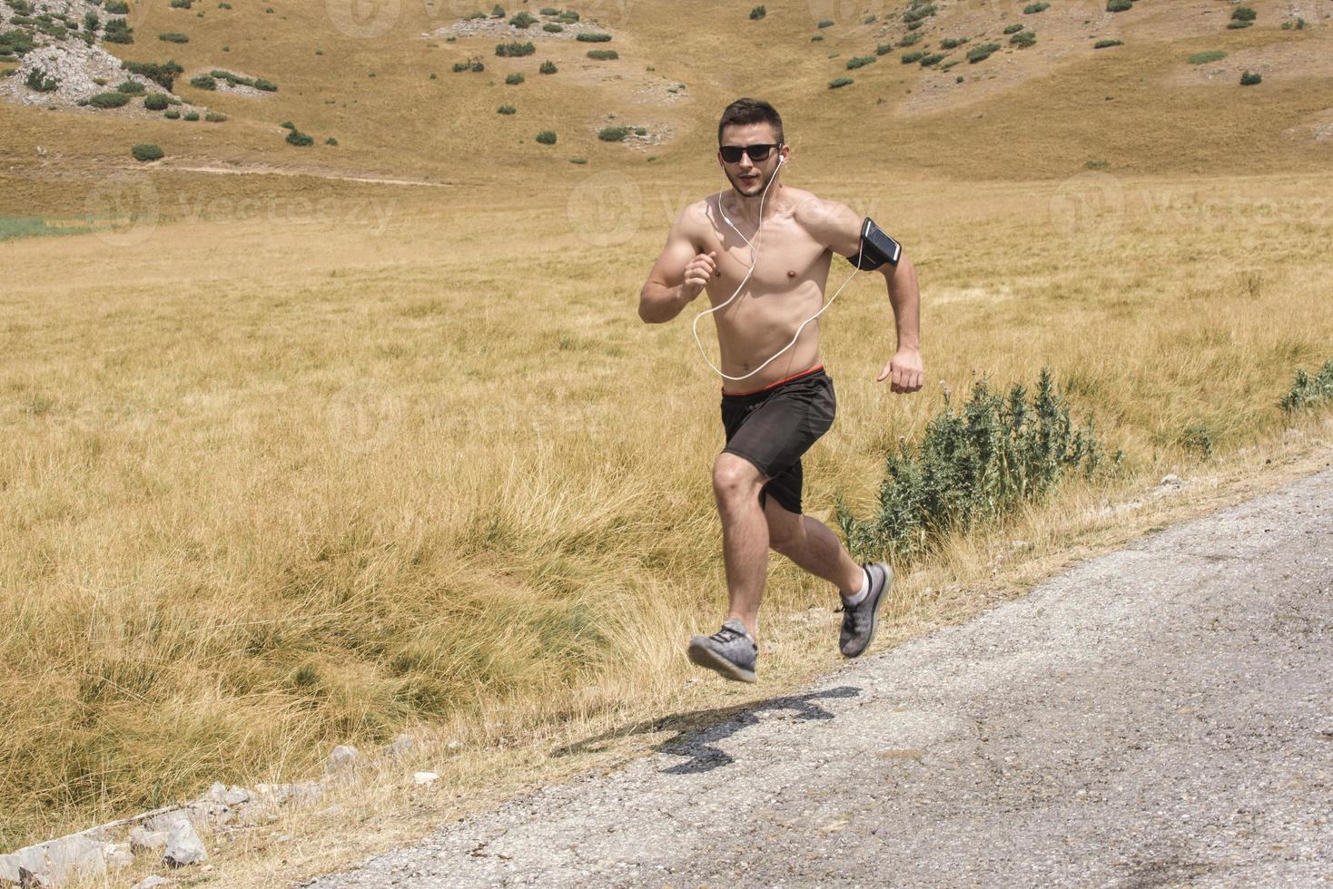 sporty man runner running on mountain plateau in summer photo