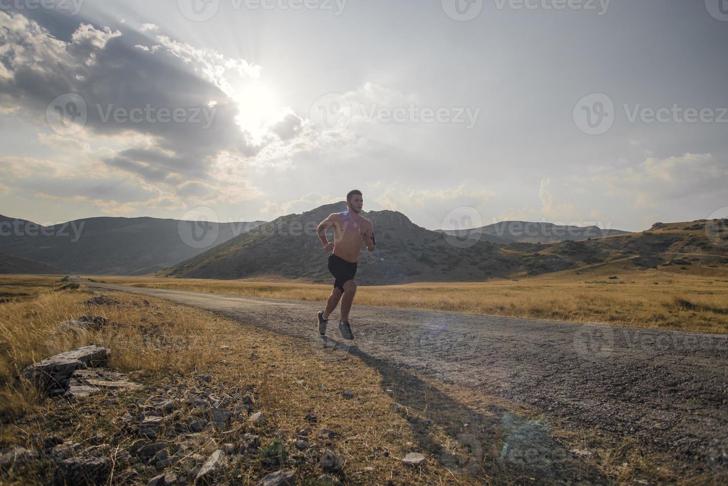 corredor de hombre deportivo corriendo en la meseta de la montaña en verano foto