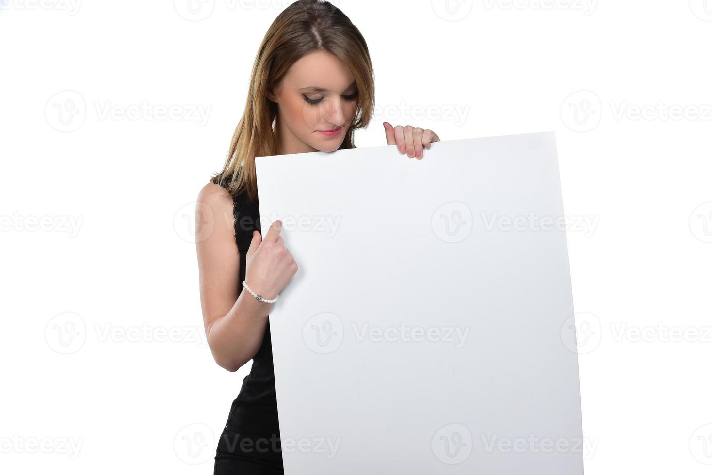 Portrait of young beautiful woman peeping at the camera holding white blank sign showing on it with finger.isolated on white photo