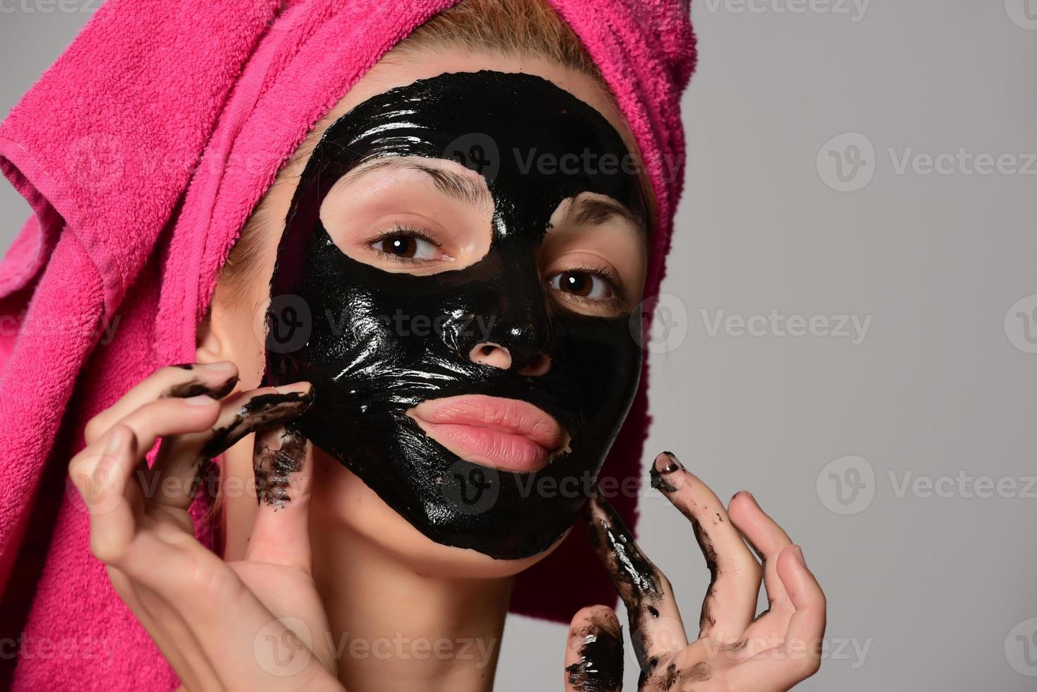 beautiful female model with black facial cosmetic mask. Isolated on gray background photo