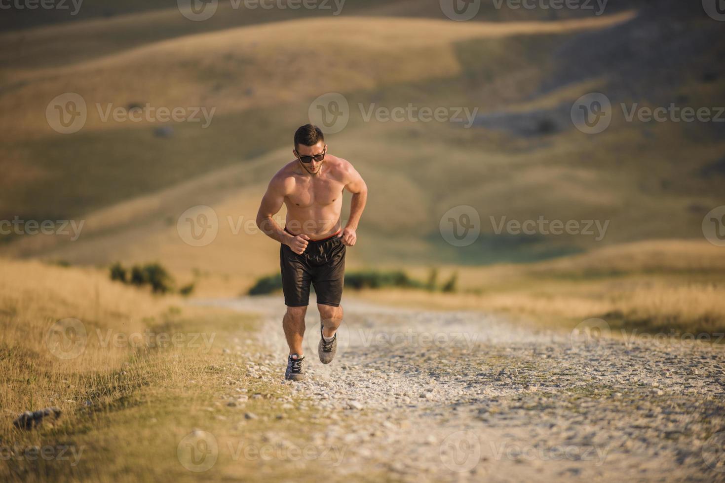 sporty man runner running on mountain plateau in summer photo