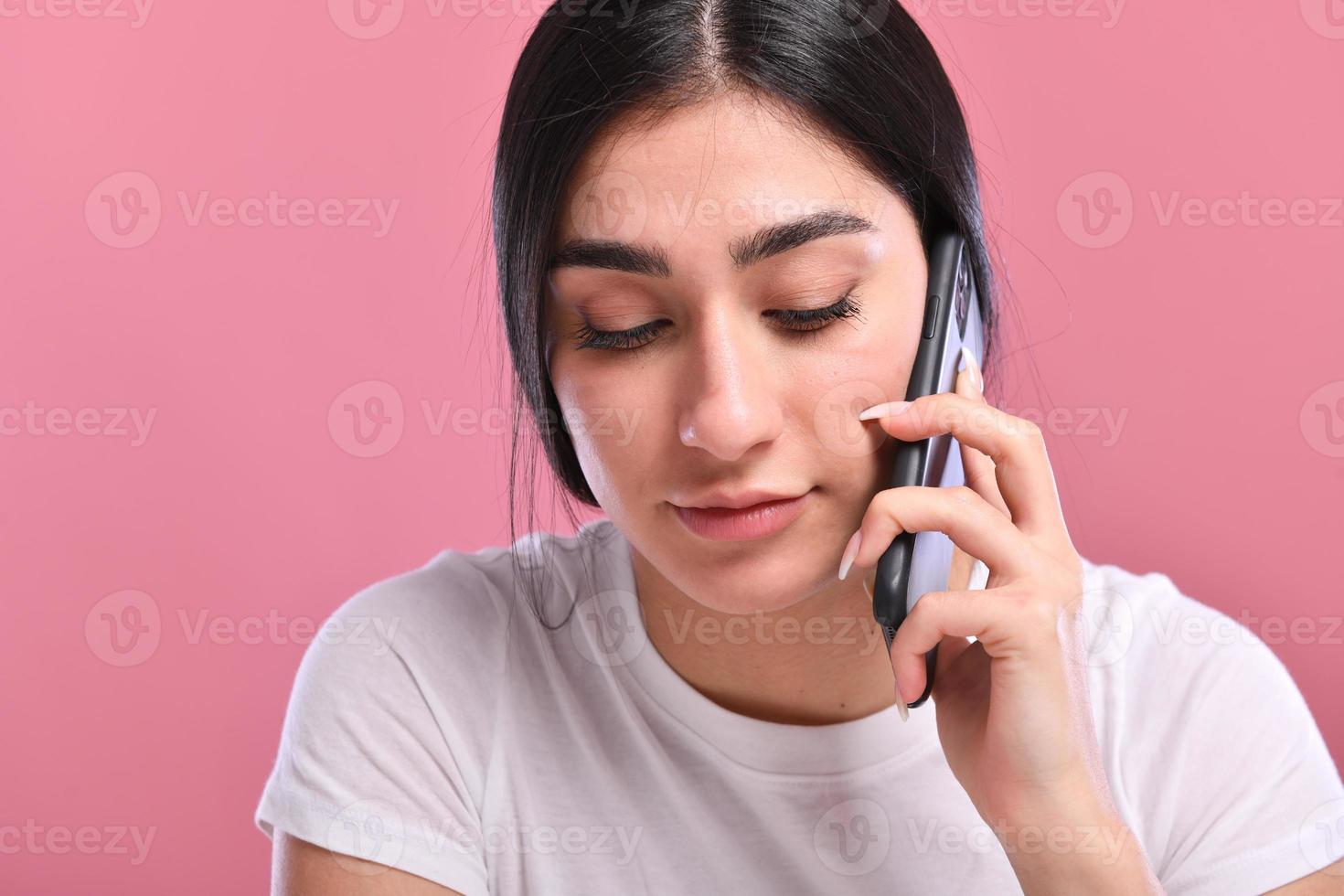 Portrait of a smiling young casual brunette woman talking on mobile phone photo