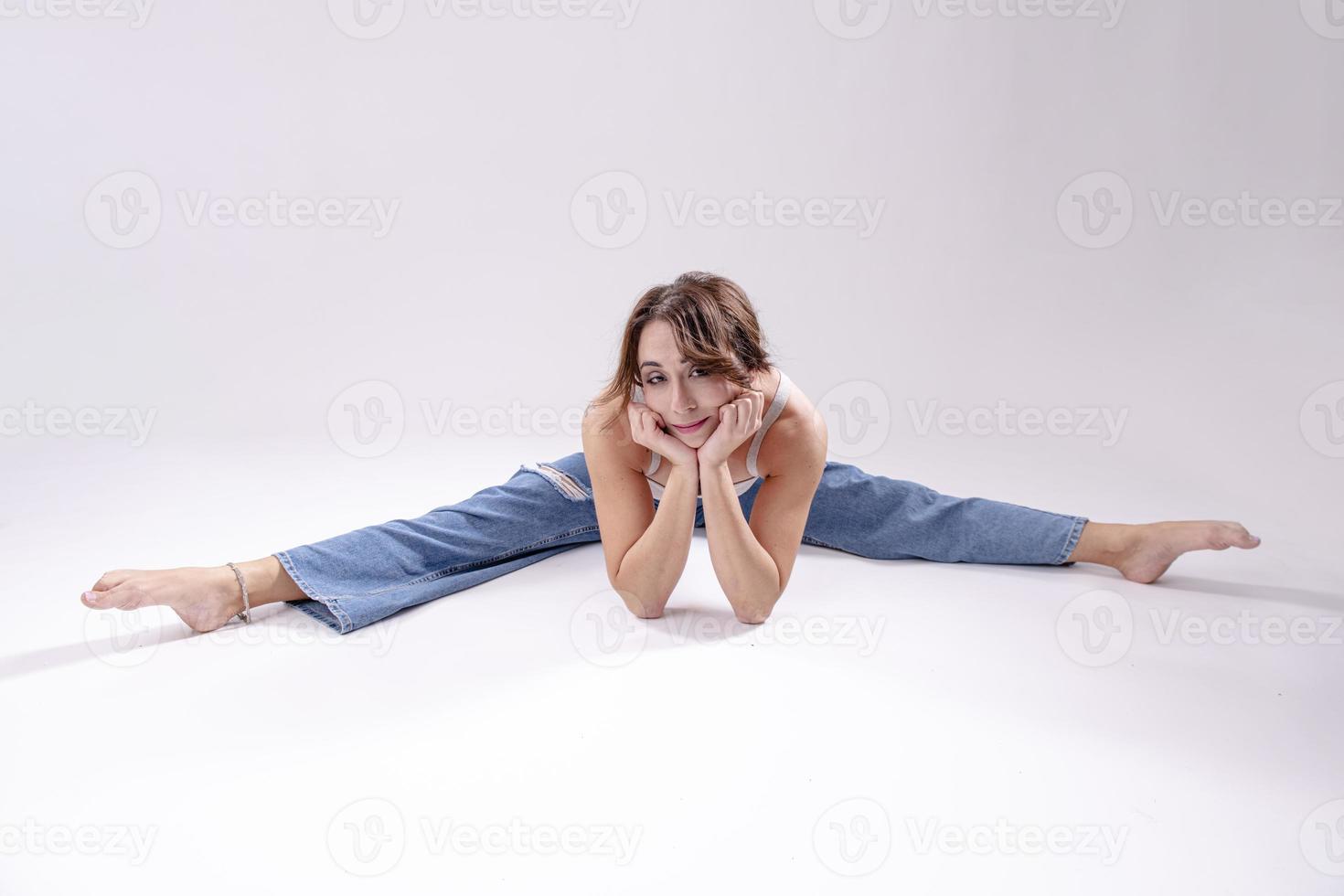 Portrait of beautiful young woman with athletic flexible body doing leg stretching. isolated photo