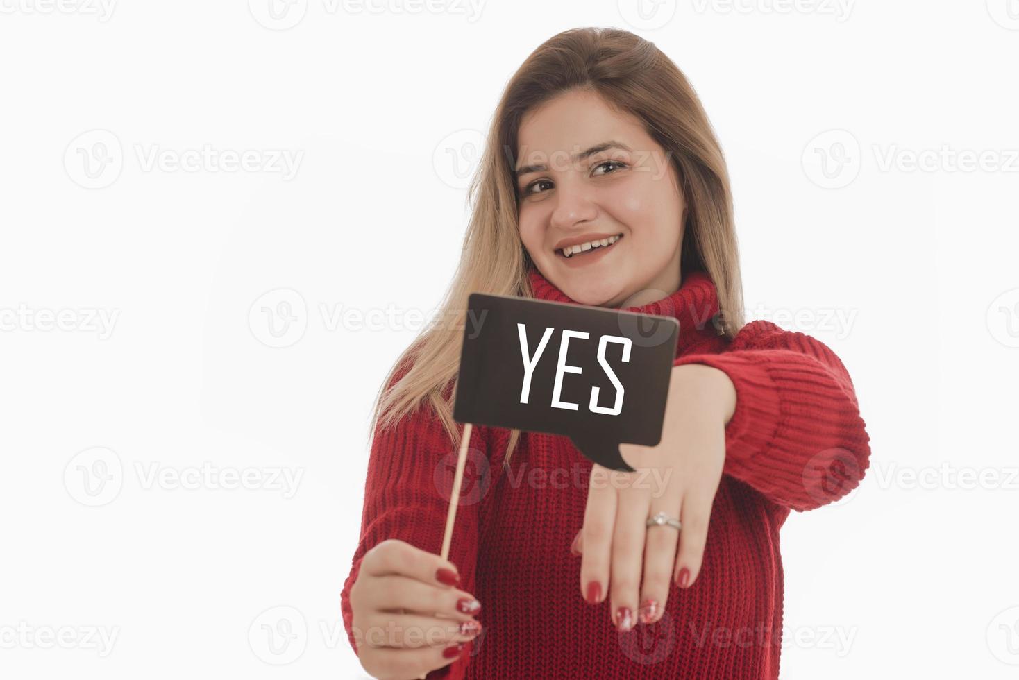 Woman holding engagement ring and sign saying YES photo