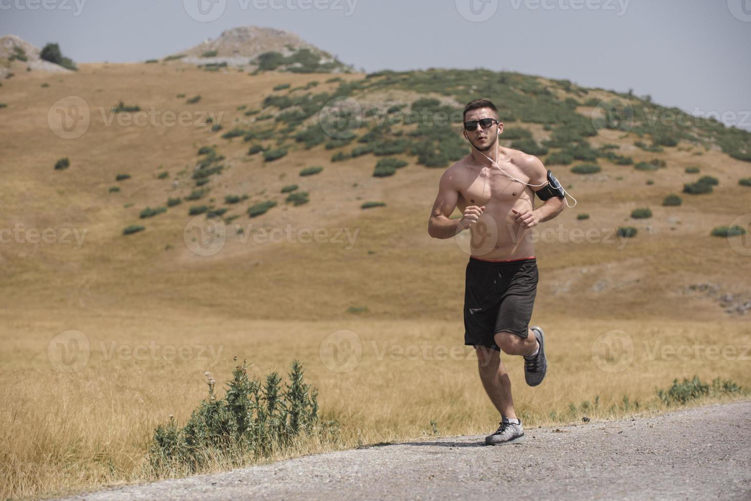 sporty man runner running on mountain plateau in summer photo