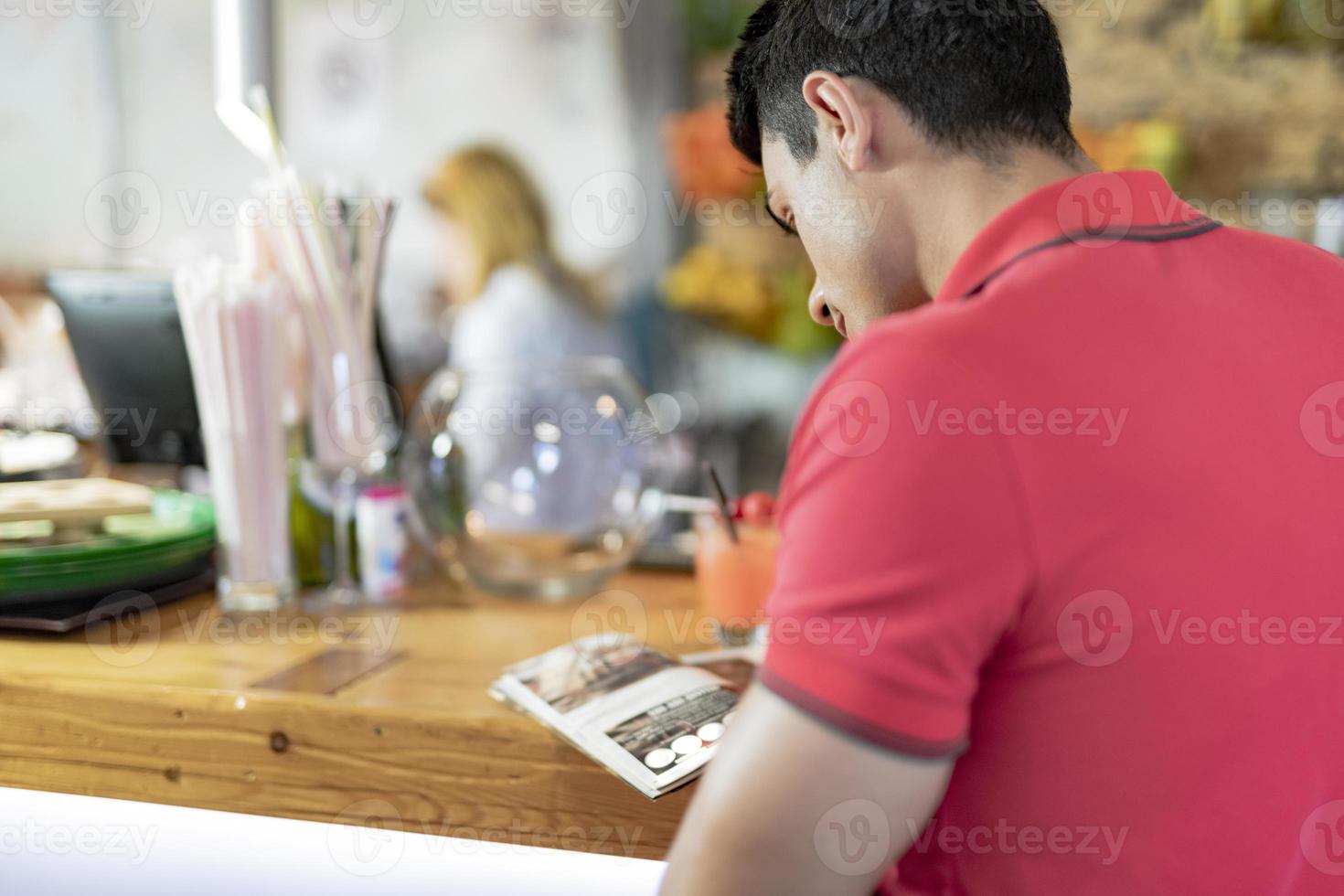 apuesto joven leyendo un libro en la barra del bar. foto