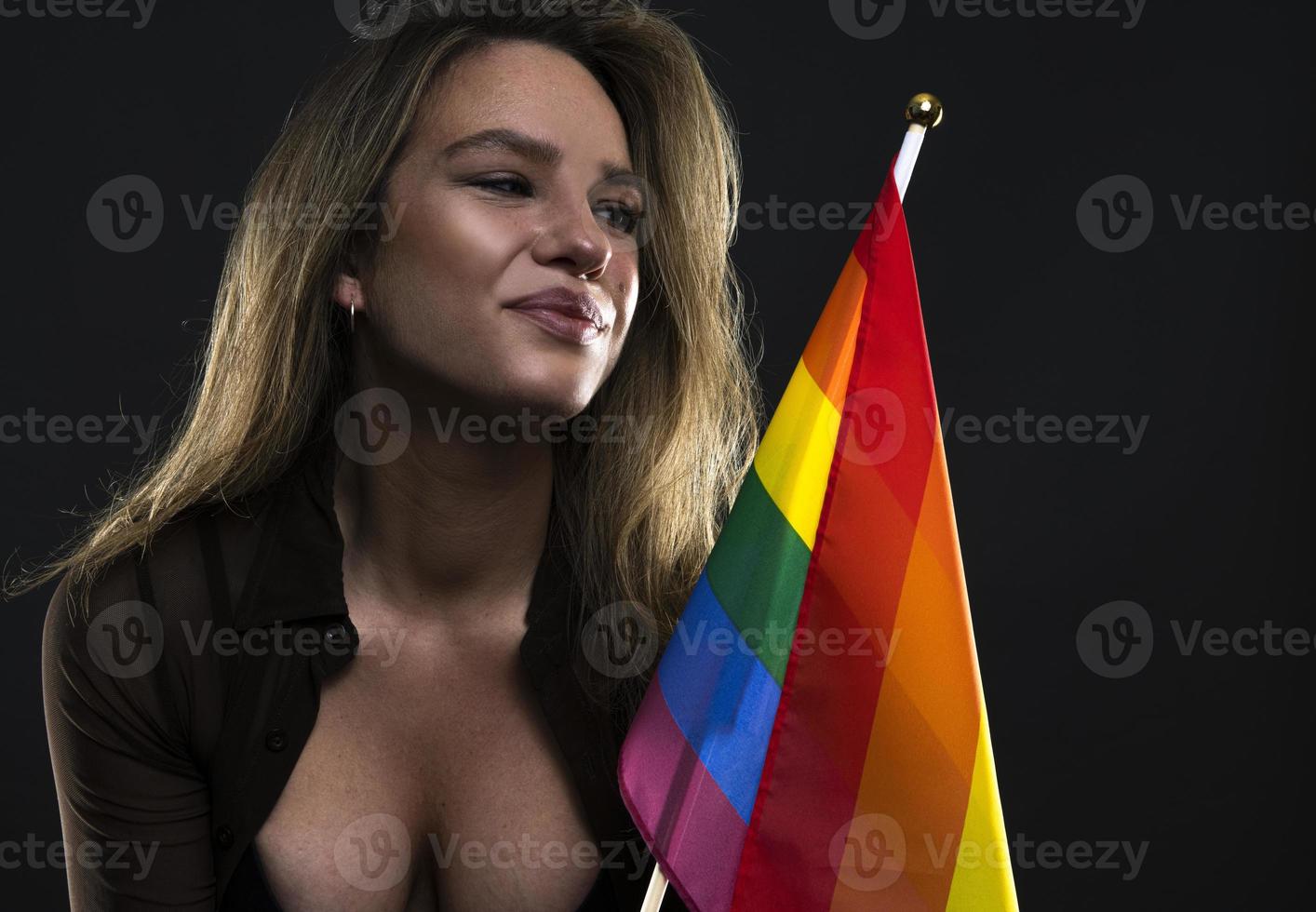 Lesbian woman holding rainbow flag isolated on black background. LGBT International symbol of the lesbian, gay, bisexual and transgender community. photo