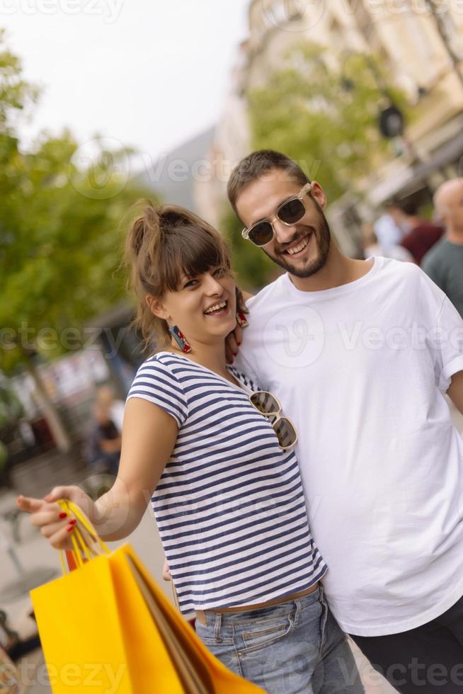 retrato de una alegre pareja joven caucásica hombre y mujer sosteniendo muchas bolsas de papel después de ir de compras mientras camina y habla en la calle. feliz pareja familiar con paquetes al aire libre. concepto de compra foto