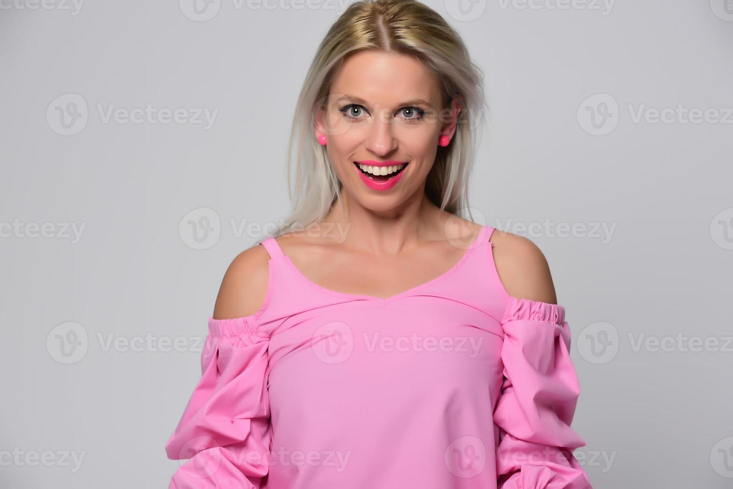 Portrait of beautiful young woman in cute pink shirt and blue jeans posing in studio. Concept of beauty, emotions, facial expression, lifestyle, fashion, youth culture photo