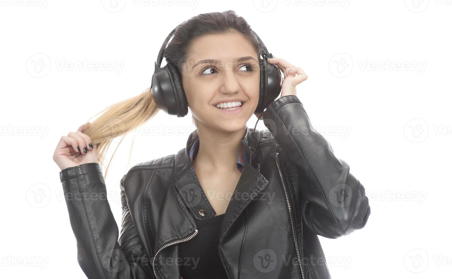 Beautiful modern girl singing favorite song, listening to music in wireless headphones, smiling and dancing photo