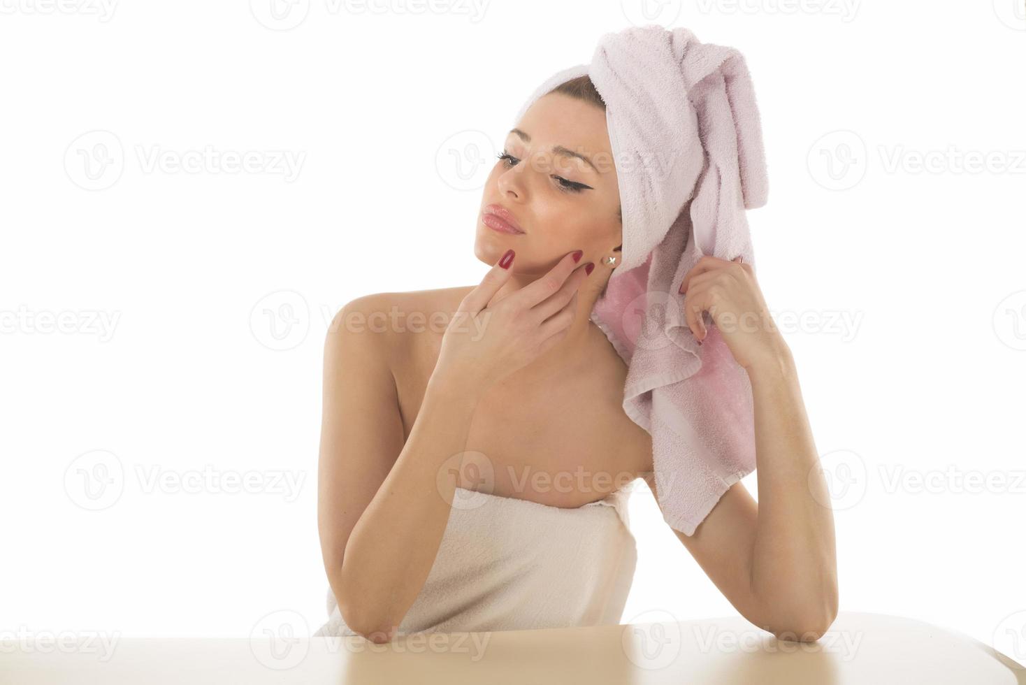 Attractive young adult woman apply facial cream look in mirror, beautiful healthy lady wrapped in towels put moisturizing lifting nourishing day creeme on soft hydrated moisturized skin in bathroom photo
