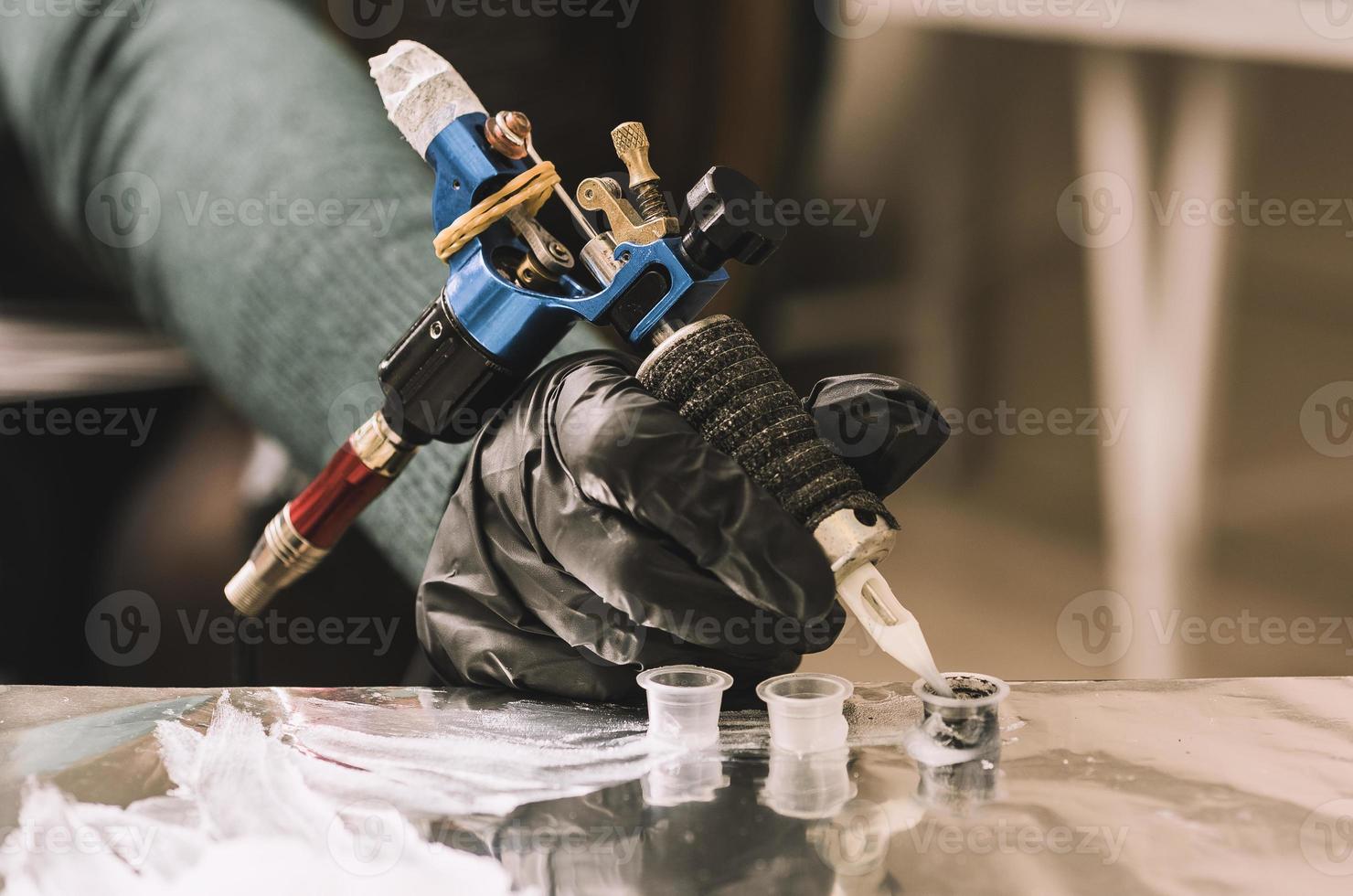 close up tattoo machine. Woman creating picture on hand with it in salon photo