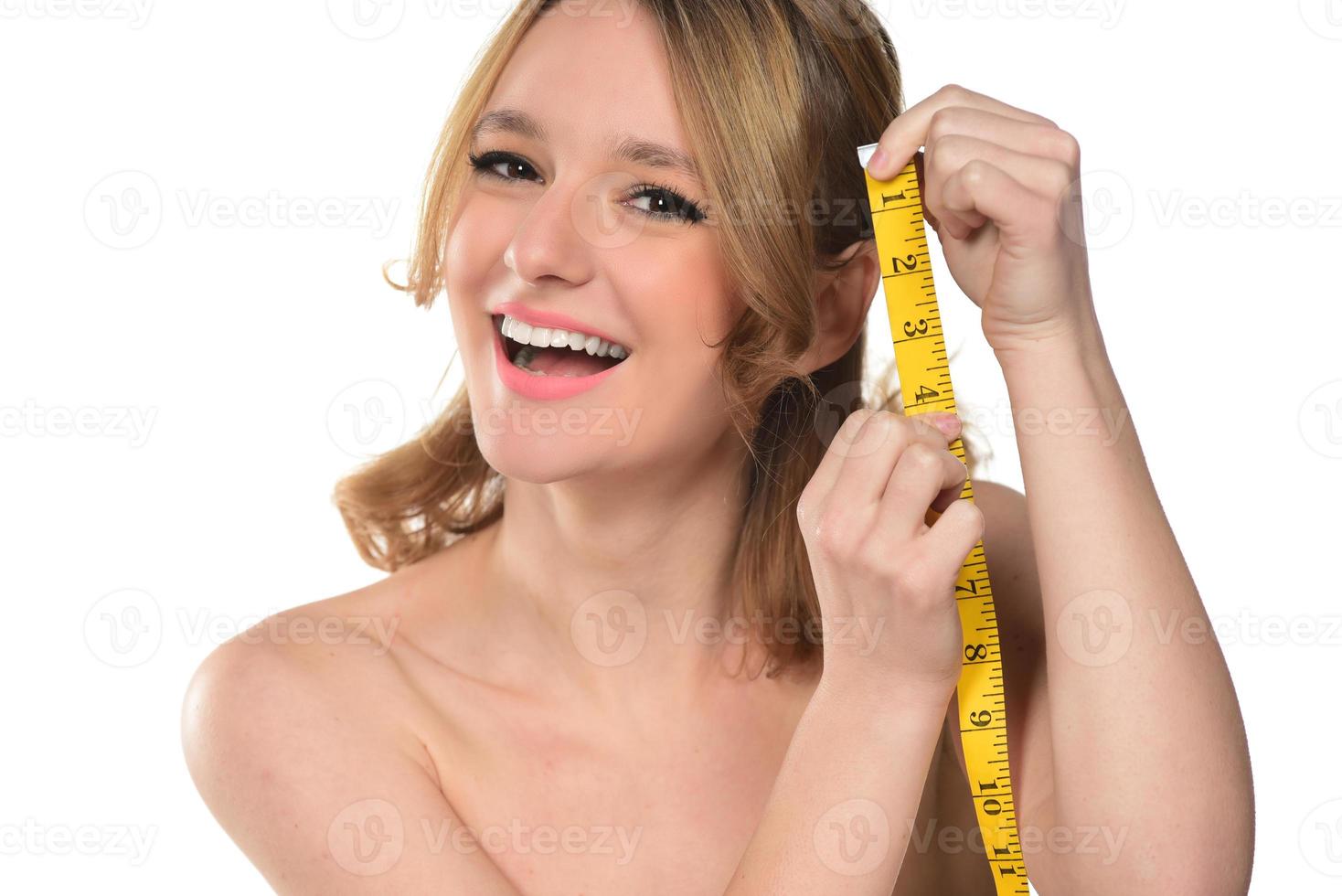 retrato de mujer hermosa con cabello rubio sosteniendo cinta dosificadora sobre fondo blanco foto