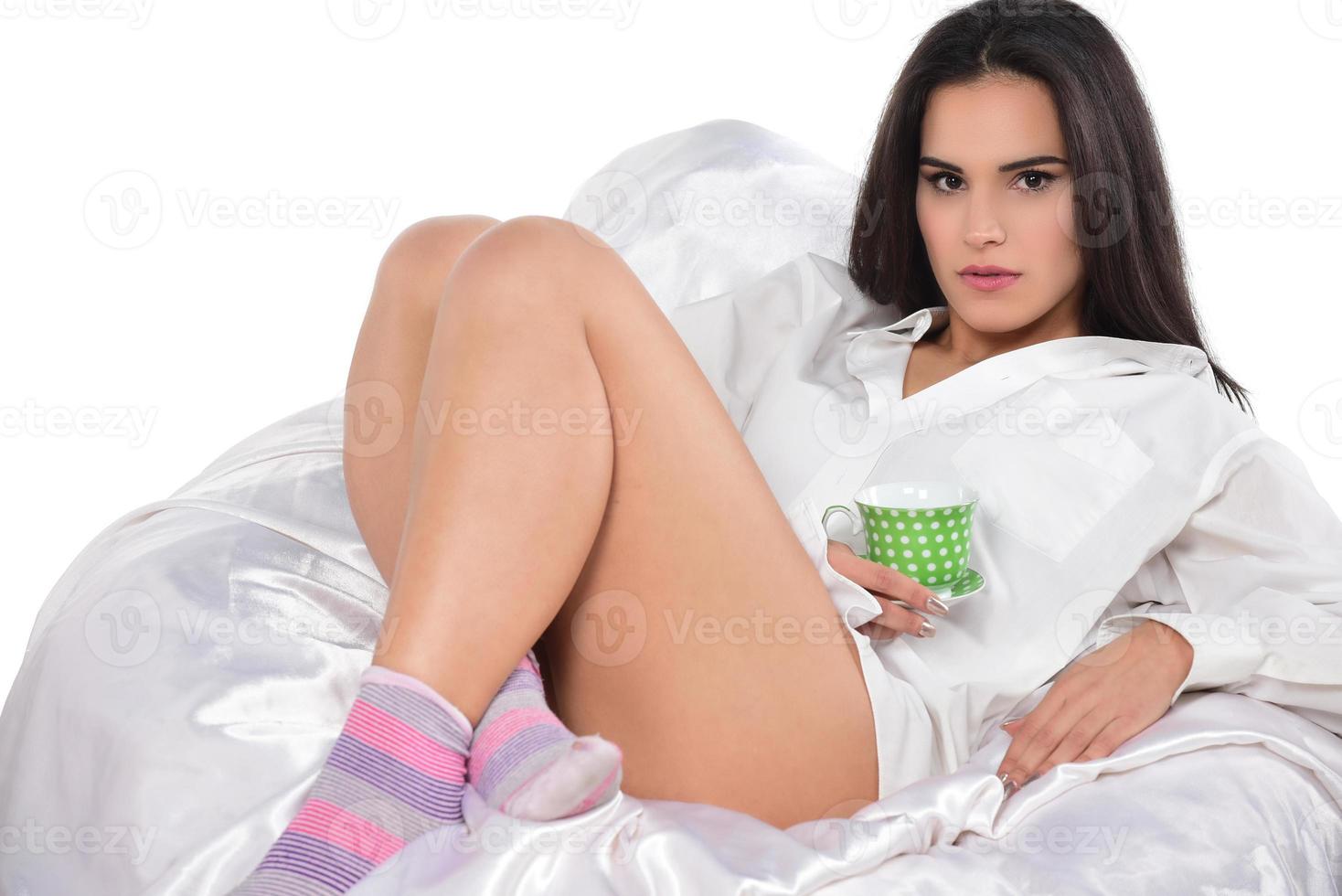 Cheerful tender female sitting with cup of coffee on be photo