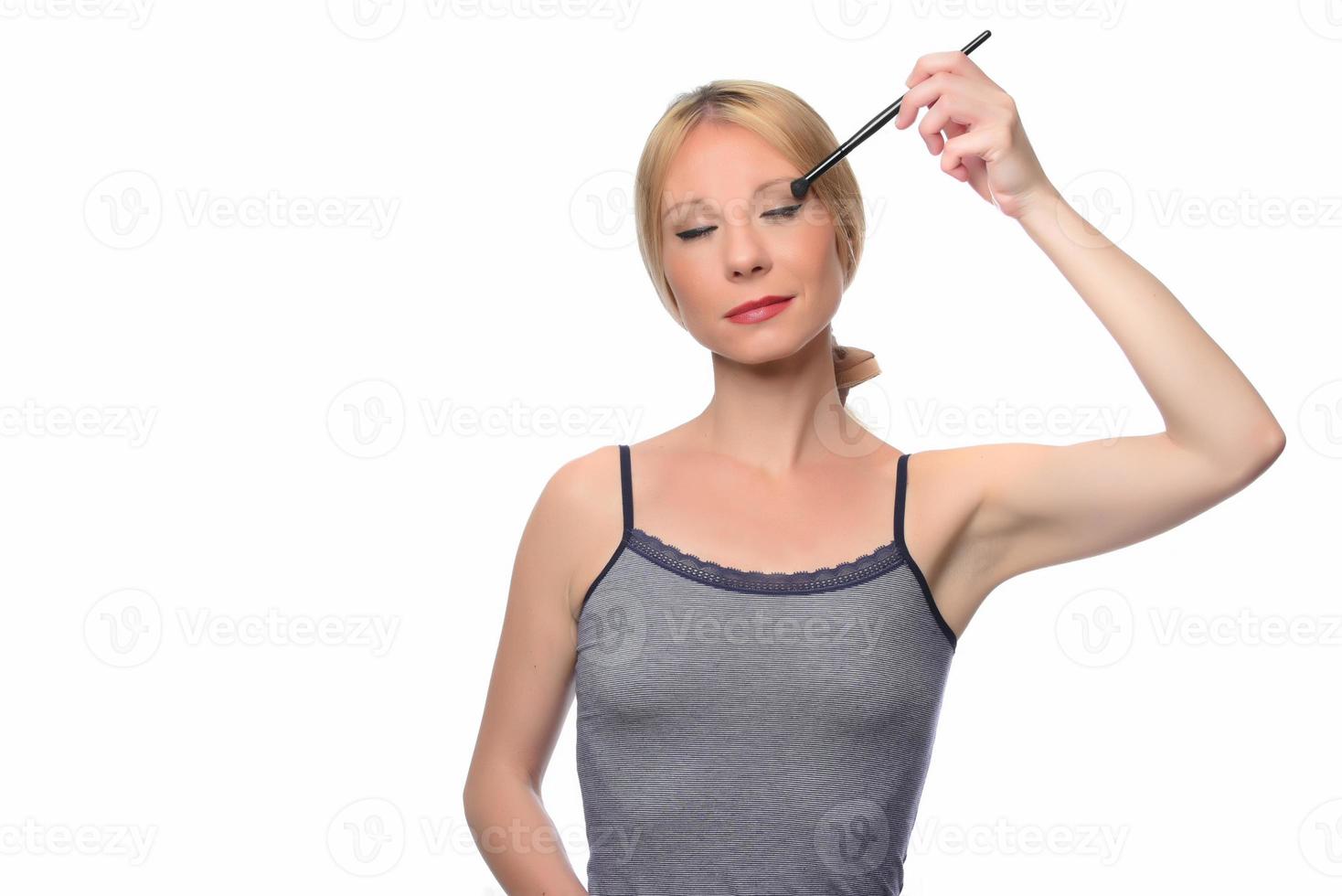 Image of joyful woman smiling at camera and using makeup brush photo