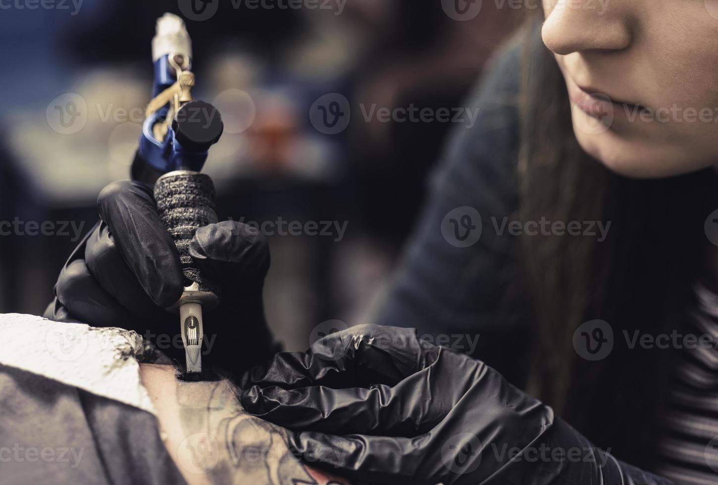 close up tattoo machine. Woman creating picture on hand with it in salon photo