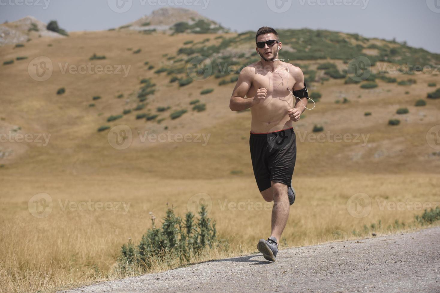 sporty man runner running on mountain plateau in summer photo