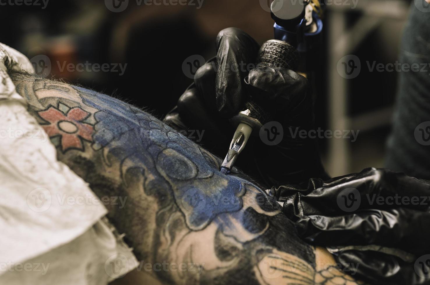 close up tattoo machine. Woman creating picture on hand with it in salon photo